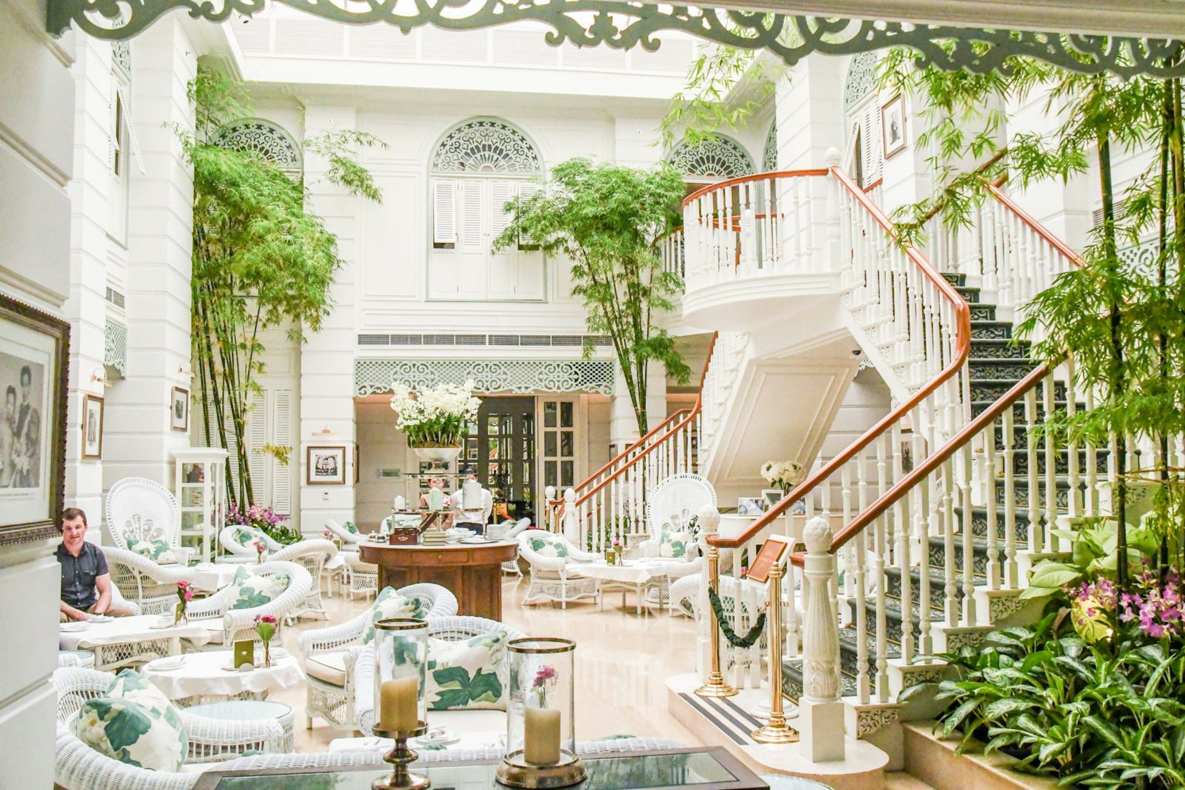 The Authors' Lounge inside the Mandarin Oriental hotel is filled with white woven chairs and plants scattered throughout the room.