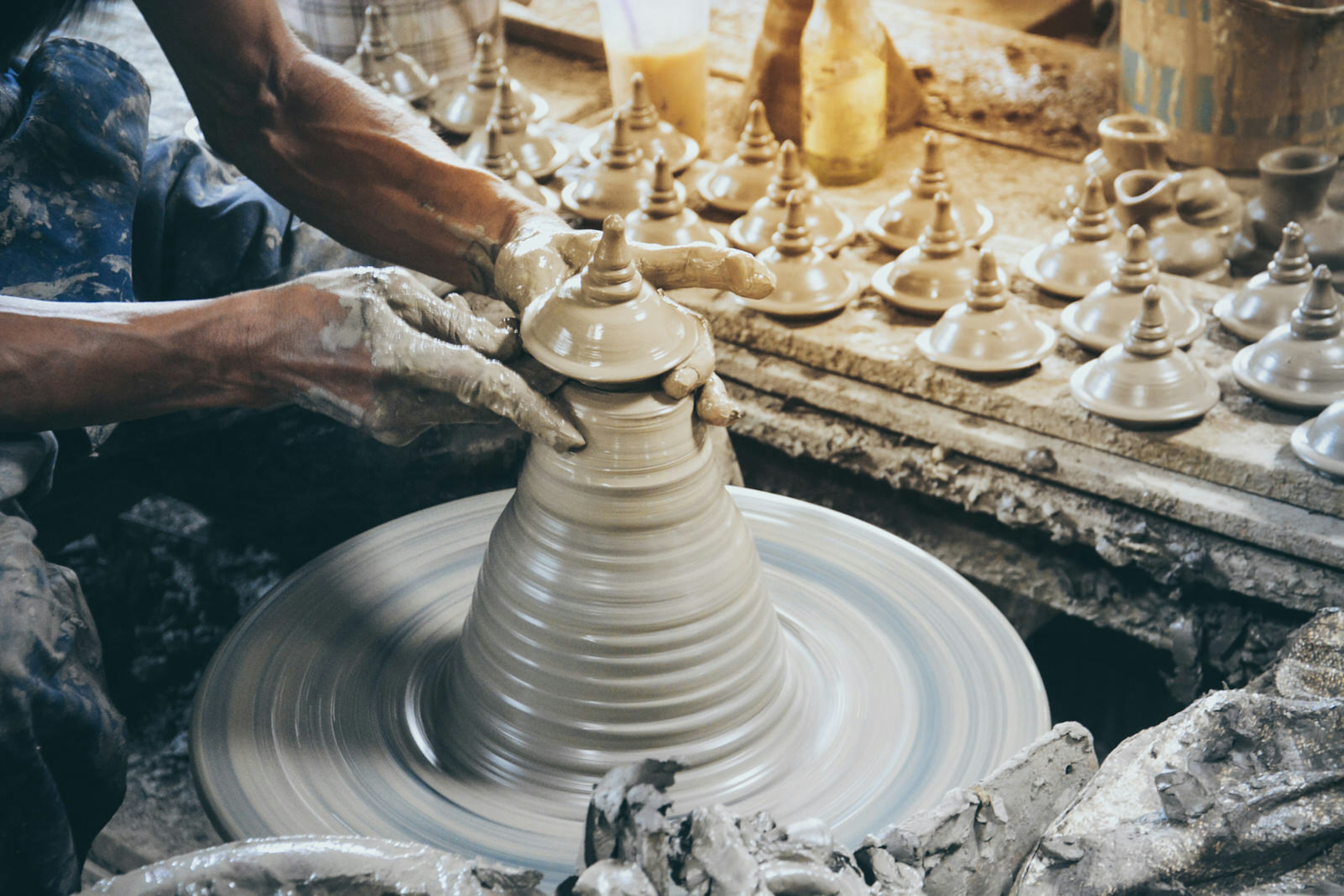 A potter making a Thai-style pot lid on a pottery wheel on the island of Ko Kret; day trips from Bangkok