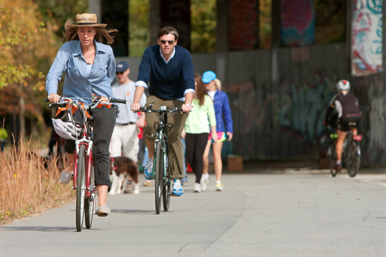 A couple rides bikes under an overpass that is part of the 22- mile Atlanta Beltline, an urban redevelopment project,