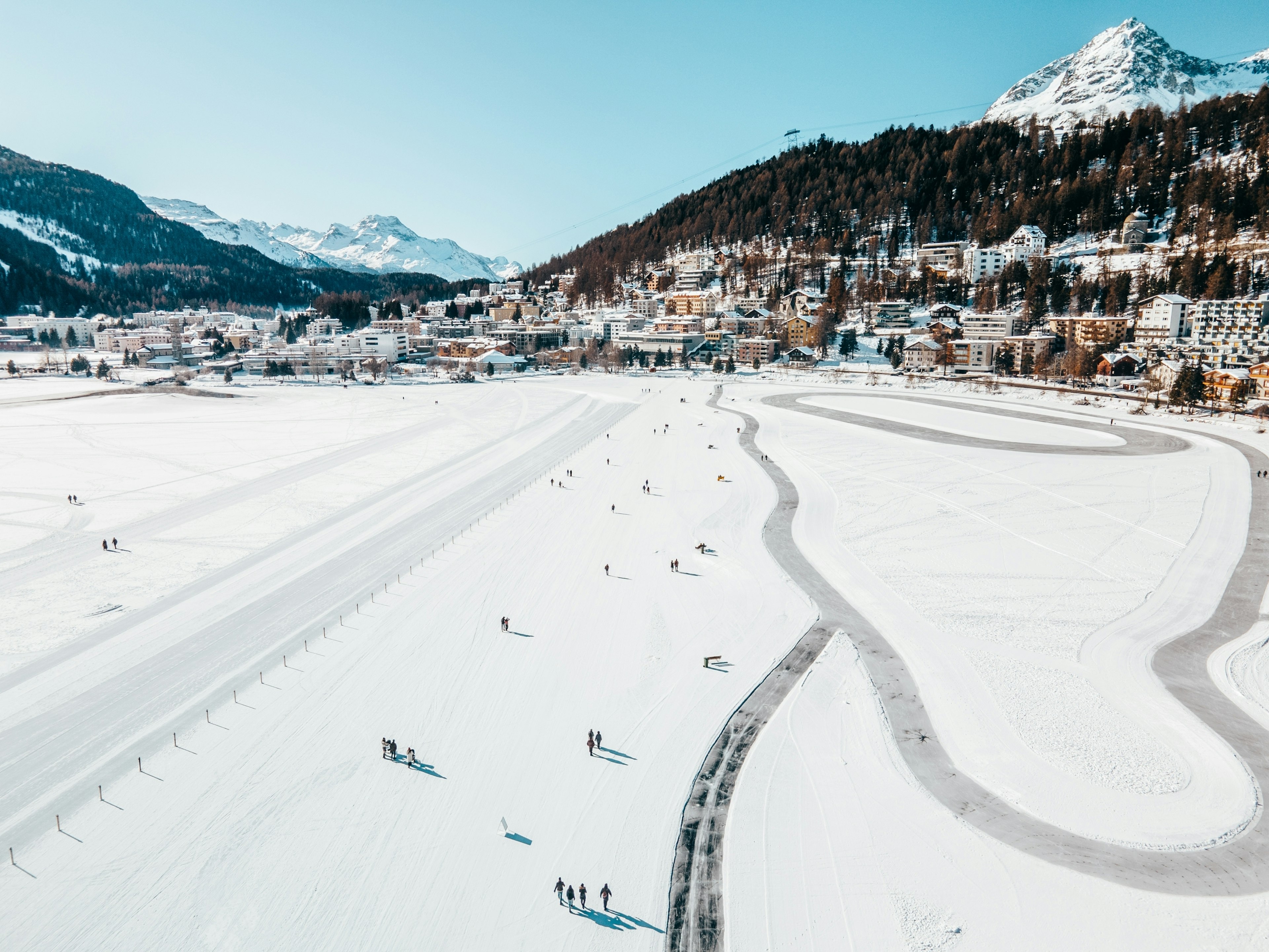 A mountain ski and snowboard resort with people out on a frozen lake