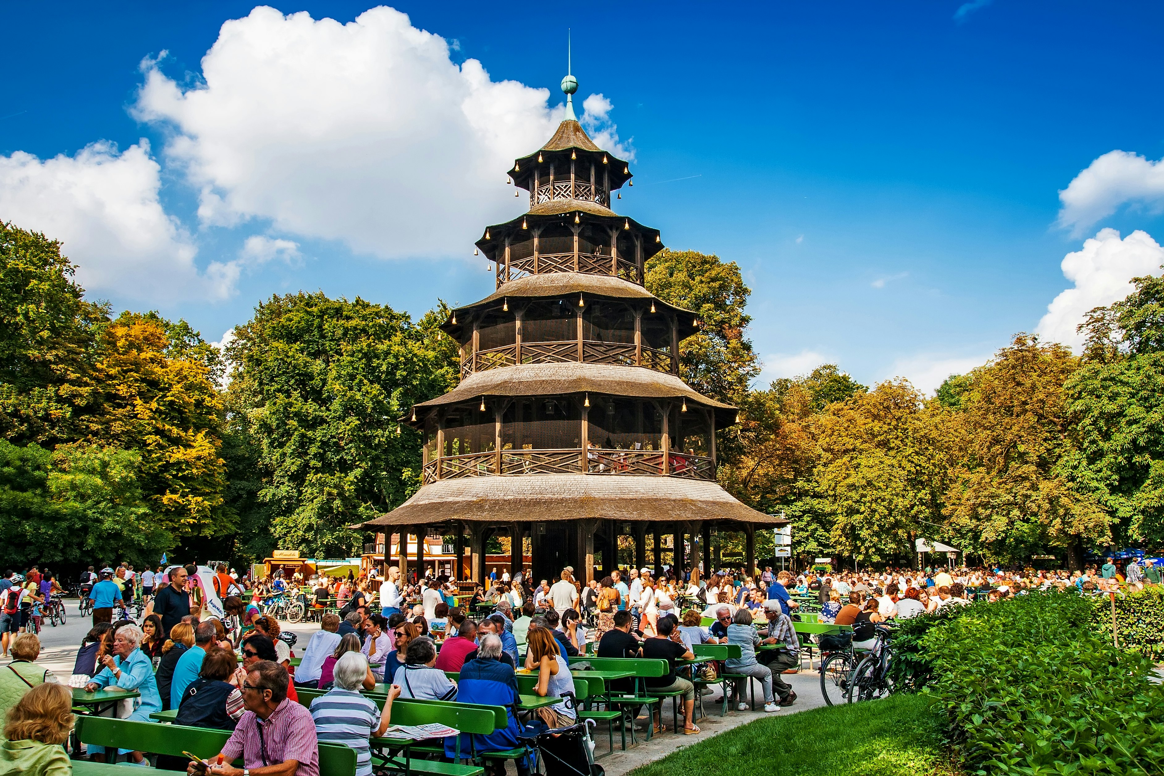 People sit at tables on a sunny day in the biergarten near the Chinese Tower of the Englischer Garten, Munich