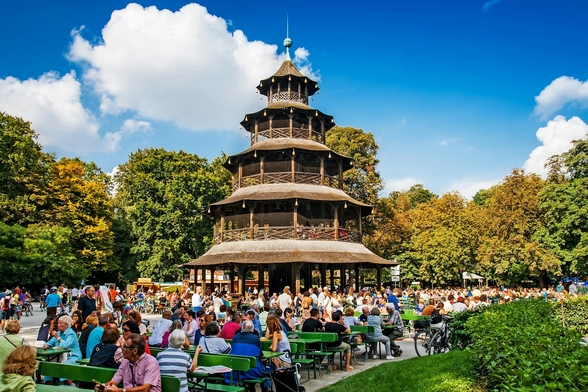 People sit at tables on a sunny day in the biergarten near the Chinese Tower of the Englischer Garten, Munich