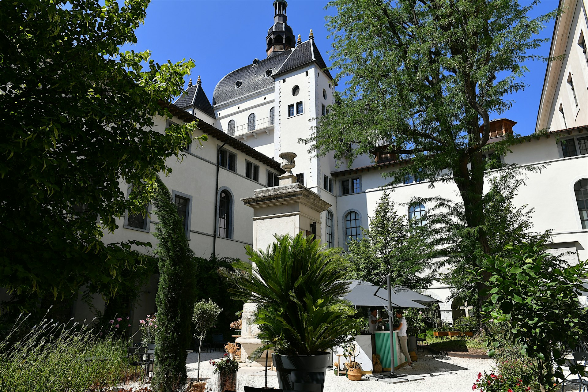 A visitor orders from a bar surrounded by trees in an inner courtyard of the former hospital Hotel-Dieu in Lyon