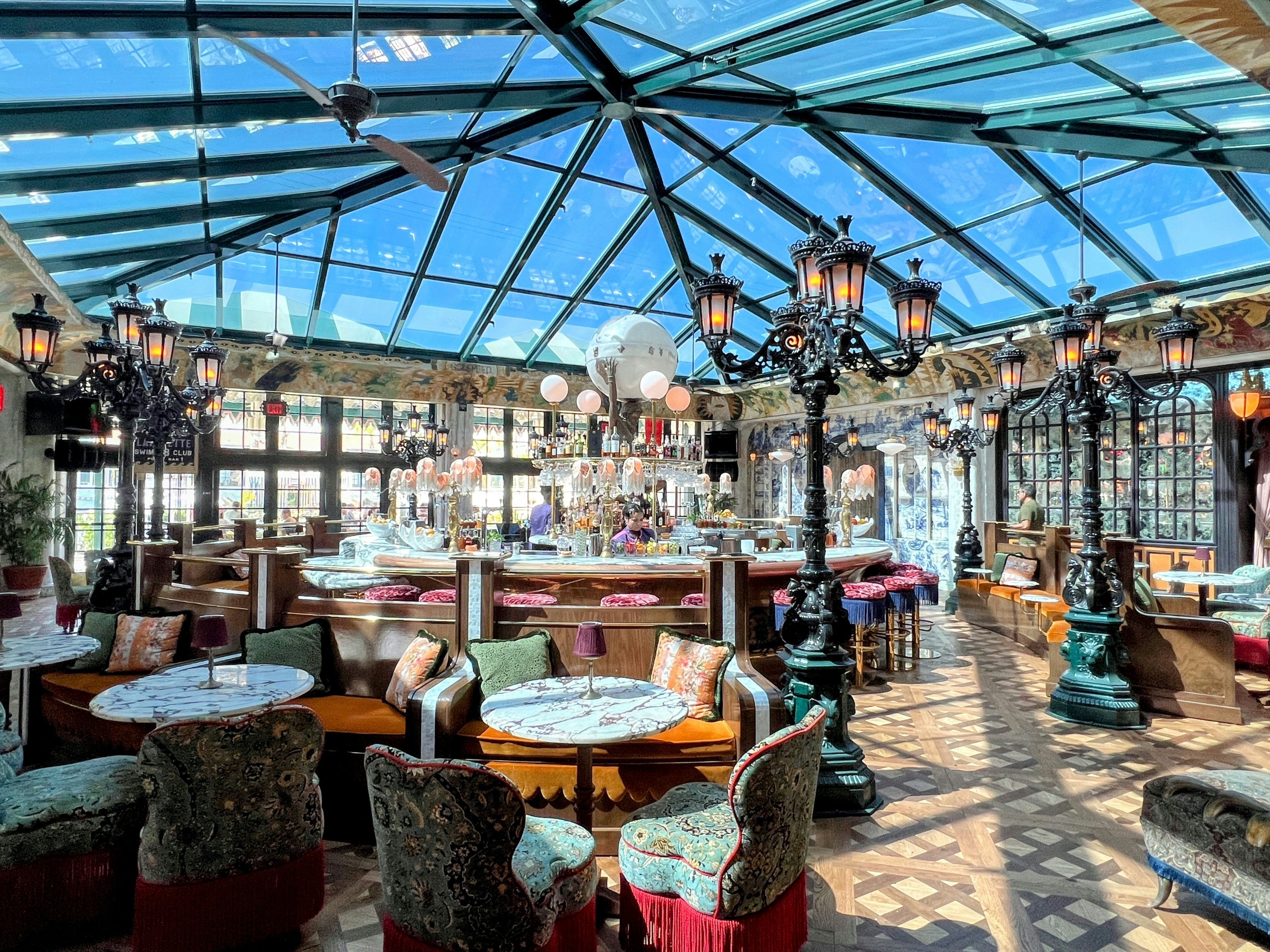 A stylish restaurant in a hotel, with a glass conservatory roof and 1940s-style decor