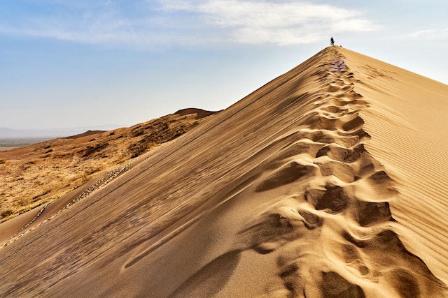 A man standing on the peak of the dunes at Altyn Emel National Park.