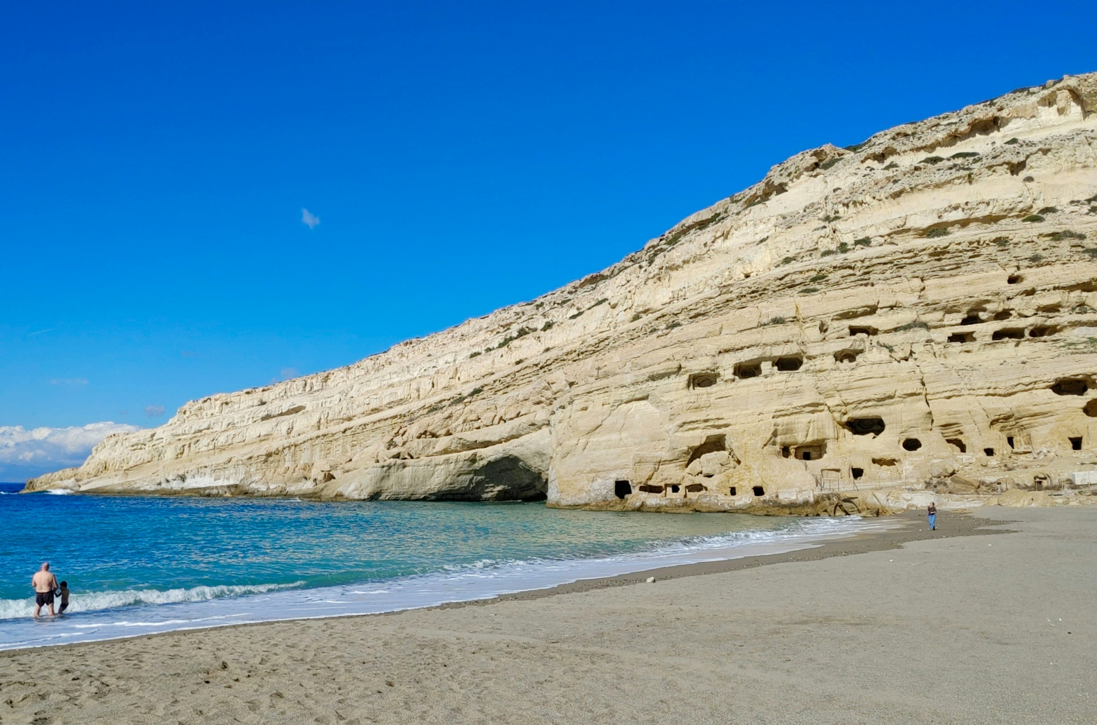 A man walks on the empty beach of Matala, Crete, in winter