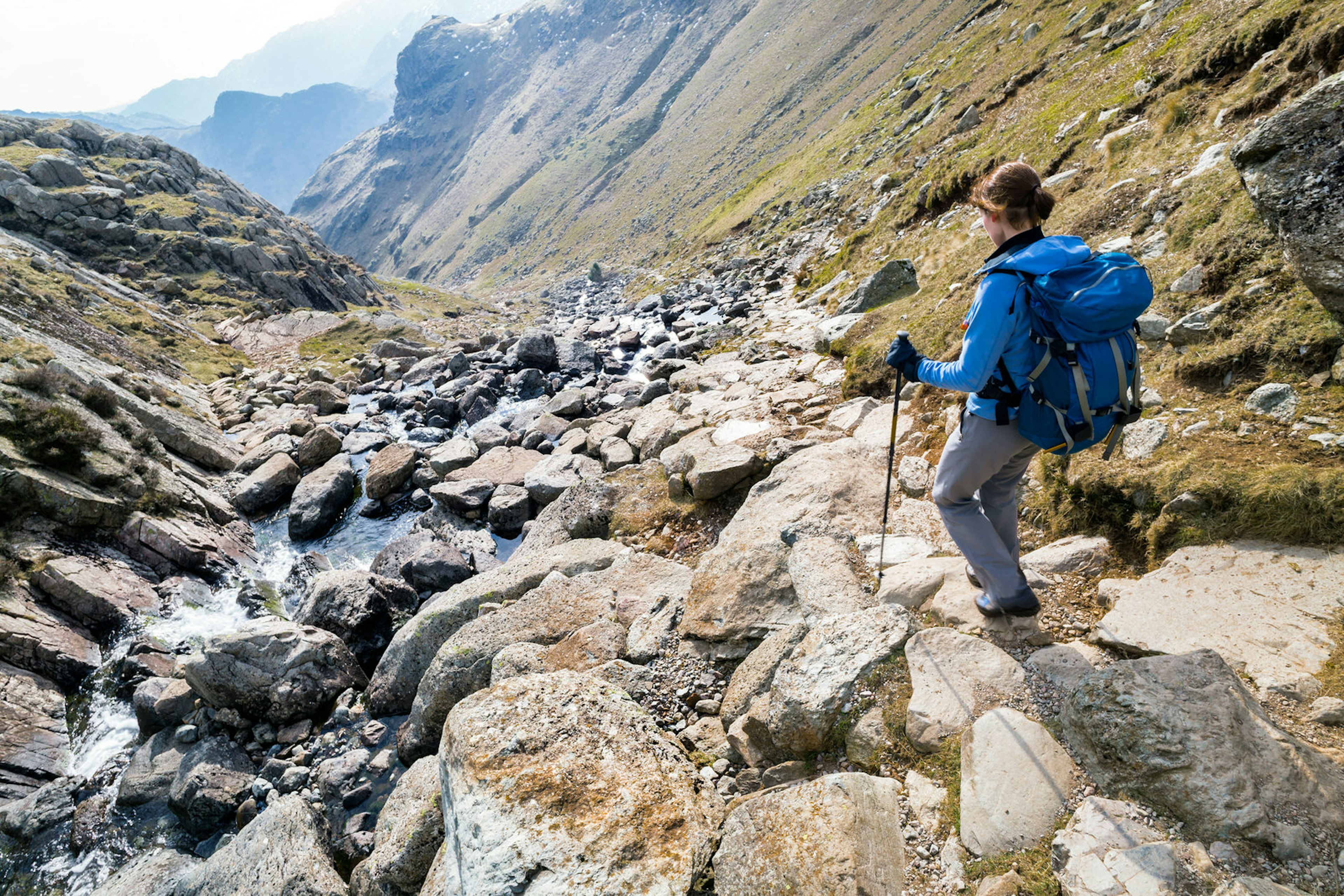 A hiker descends Stickle Ghyll, a steep trail offering views of waterfalls and lakes, in Great Langdale © Duncan Andison / Shutterstock