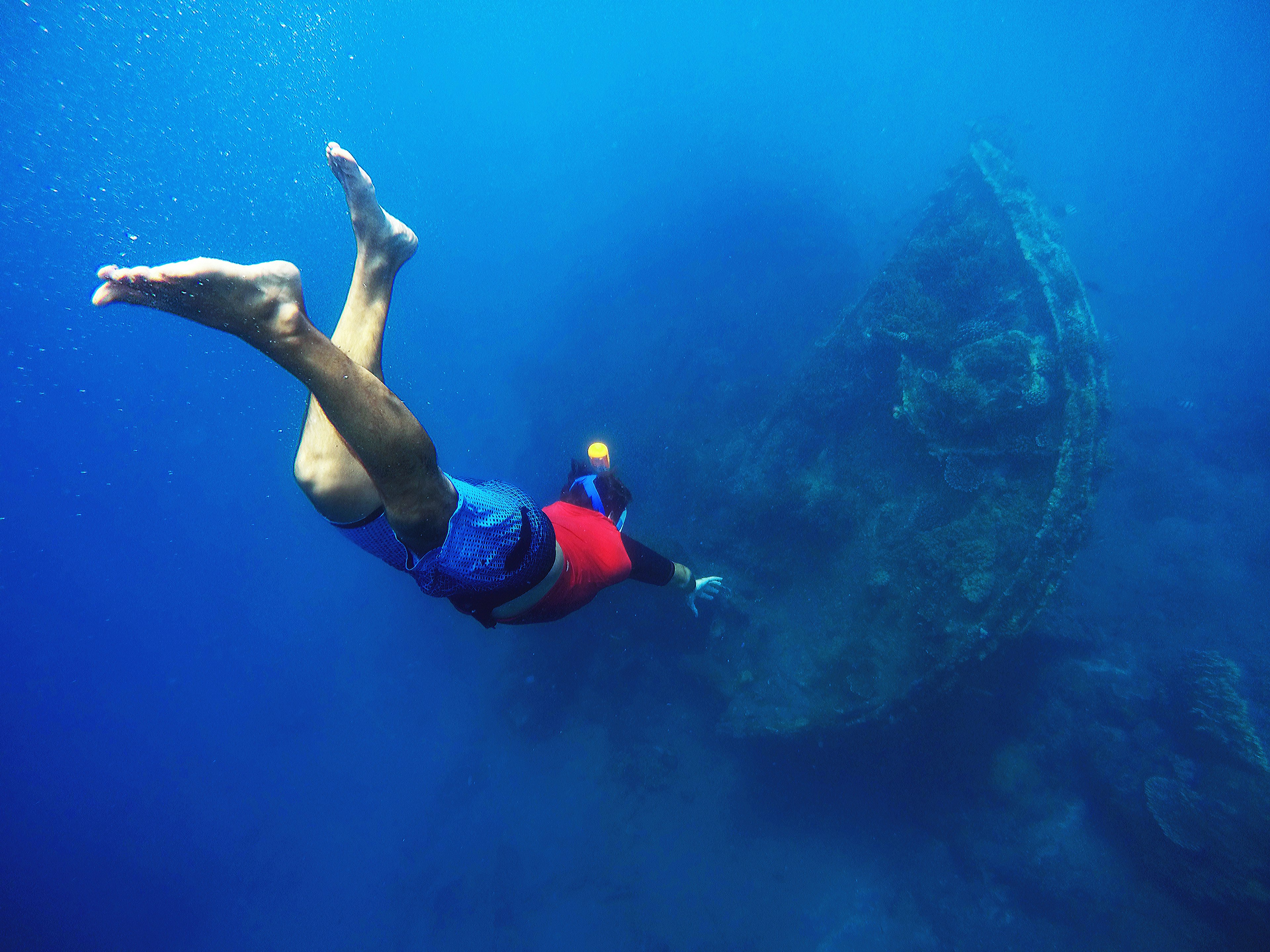 A person diving down to a shipwreck in Amed, Bali