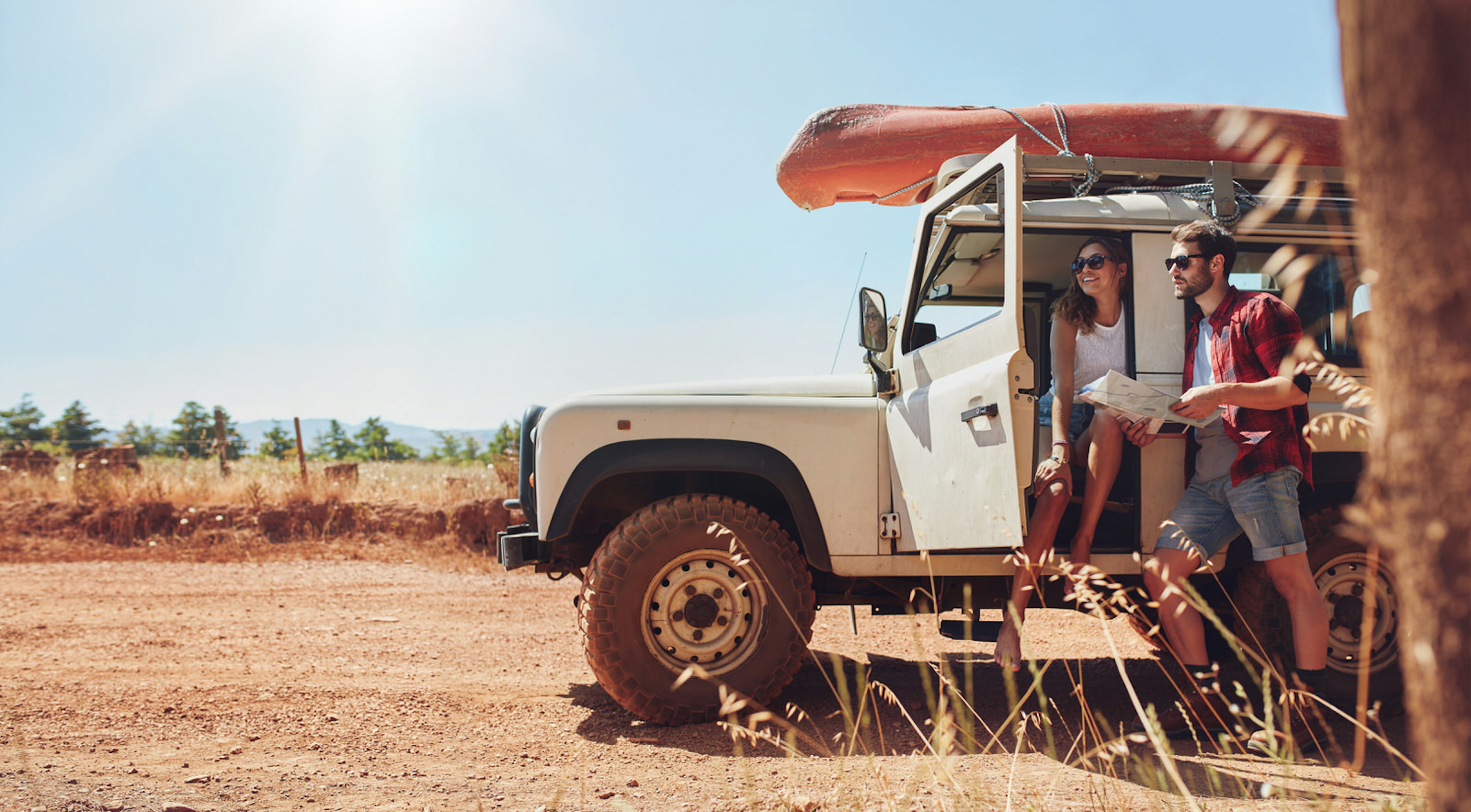 A couple driving a 4x4 take a break on a dusty roadside