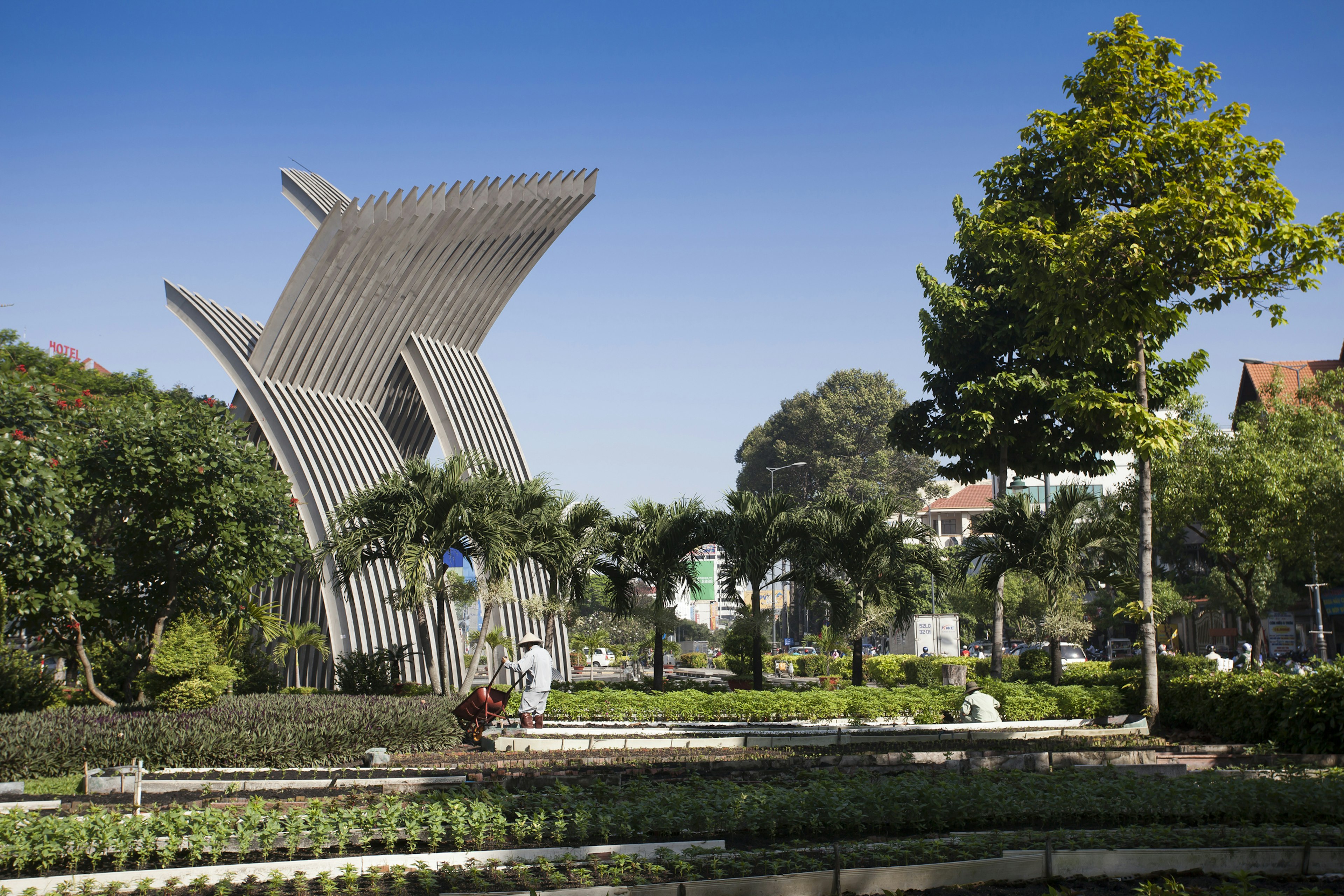 Gardeners working in parkland near a large wooden sculpture