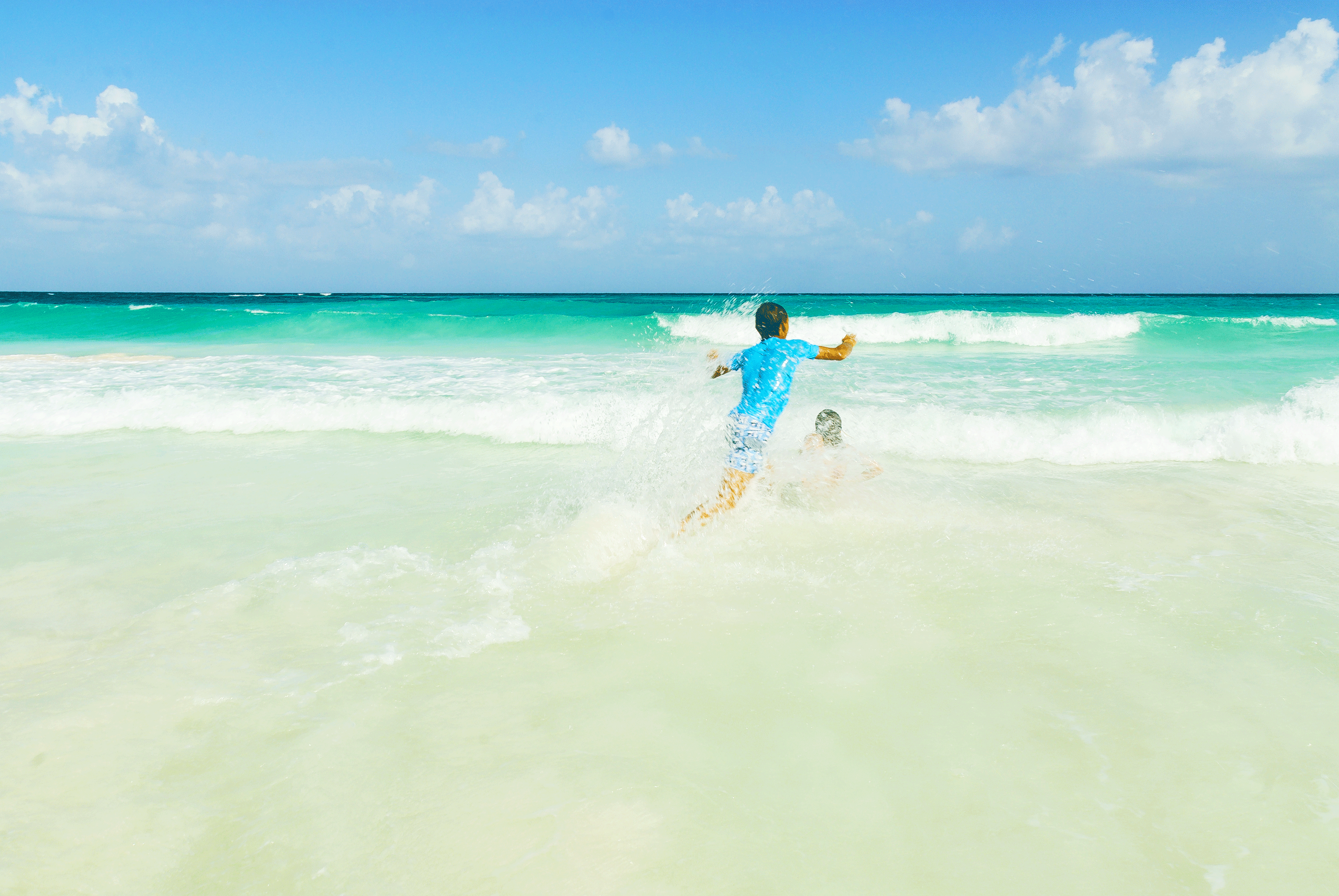 Two children play in the waves on an empty beach. ahuau19969 / Shutterstock