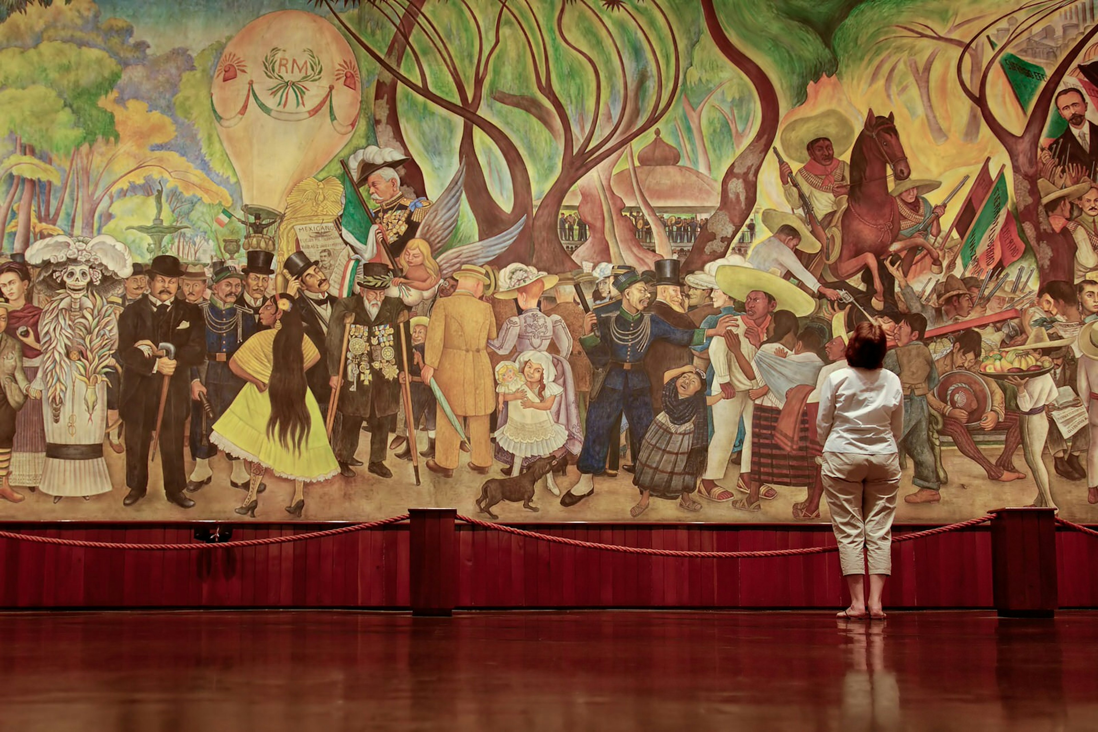 A woman stands in front of Diego Rivera’s famous mural 'Dream of a Sunday Afternoon in the Alameda Central'