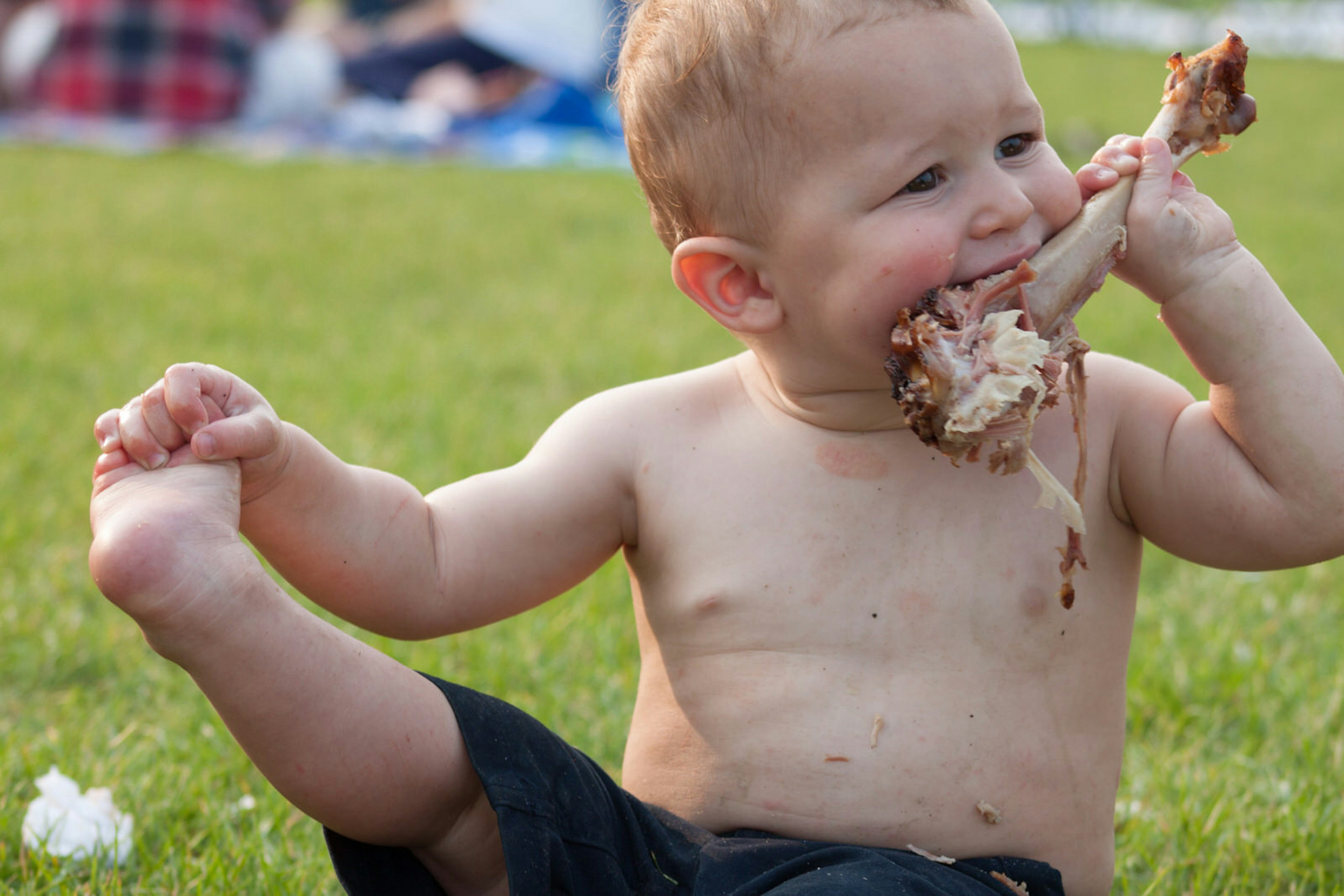 A baby eating a chicken leg at a festival© Olga Enger / Shutterstock