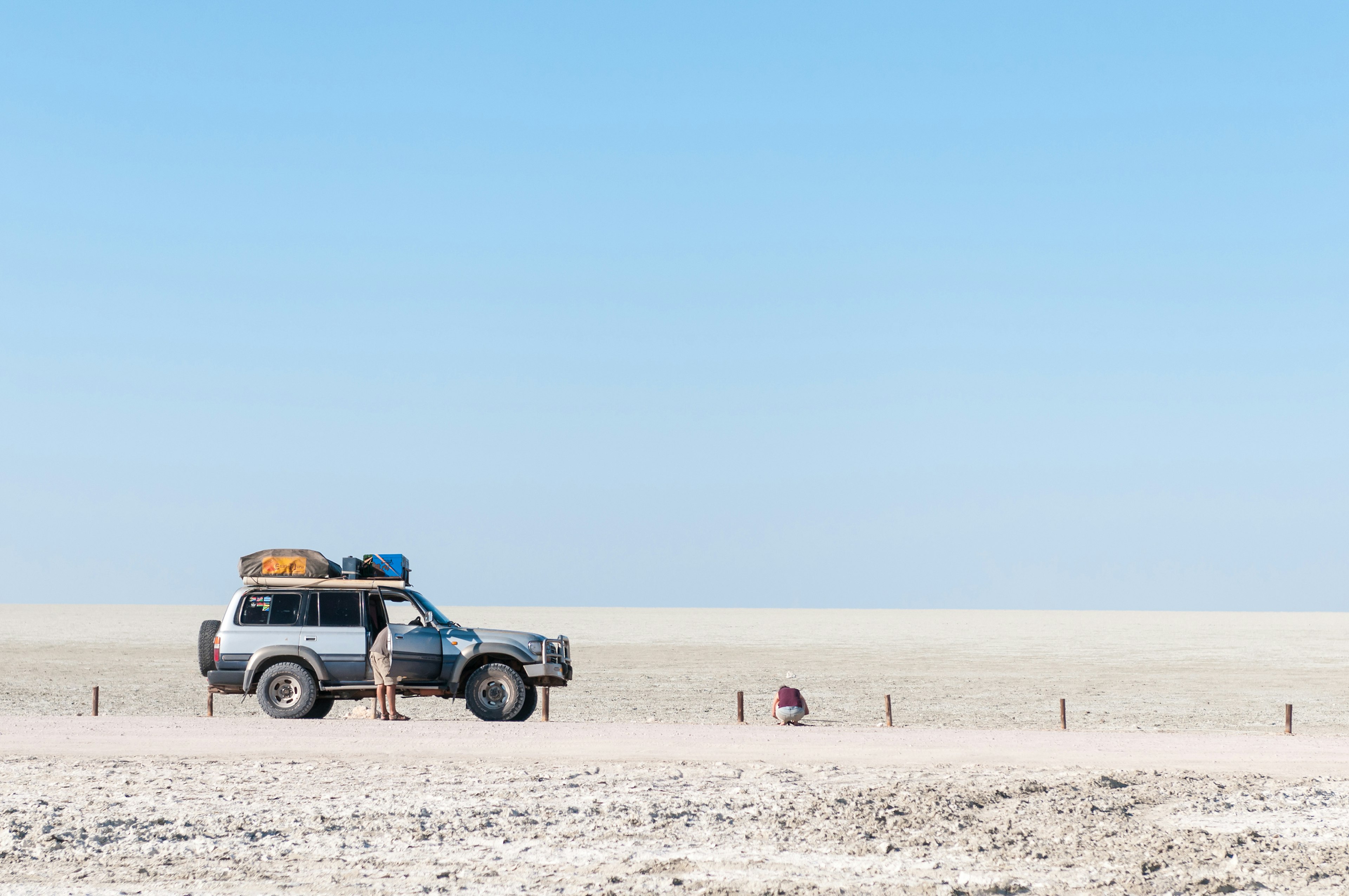 A four-wheel drive vehicle parked up on a gravel road in a flat grey landscape