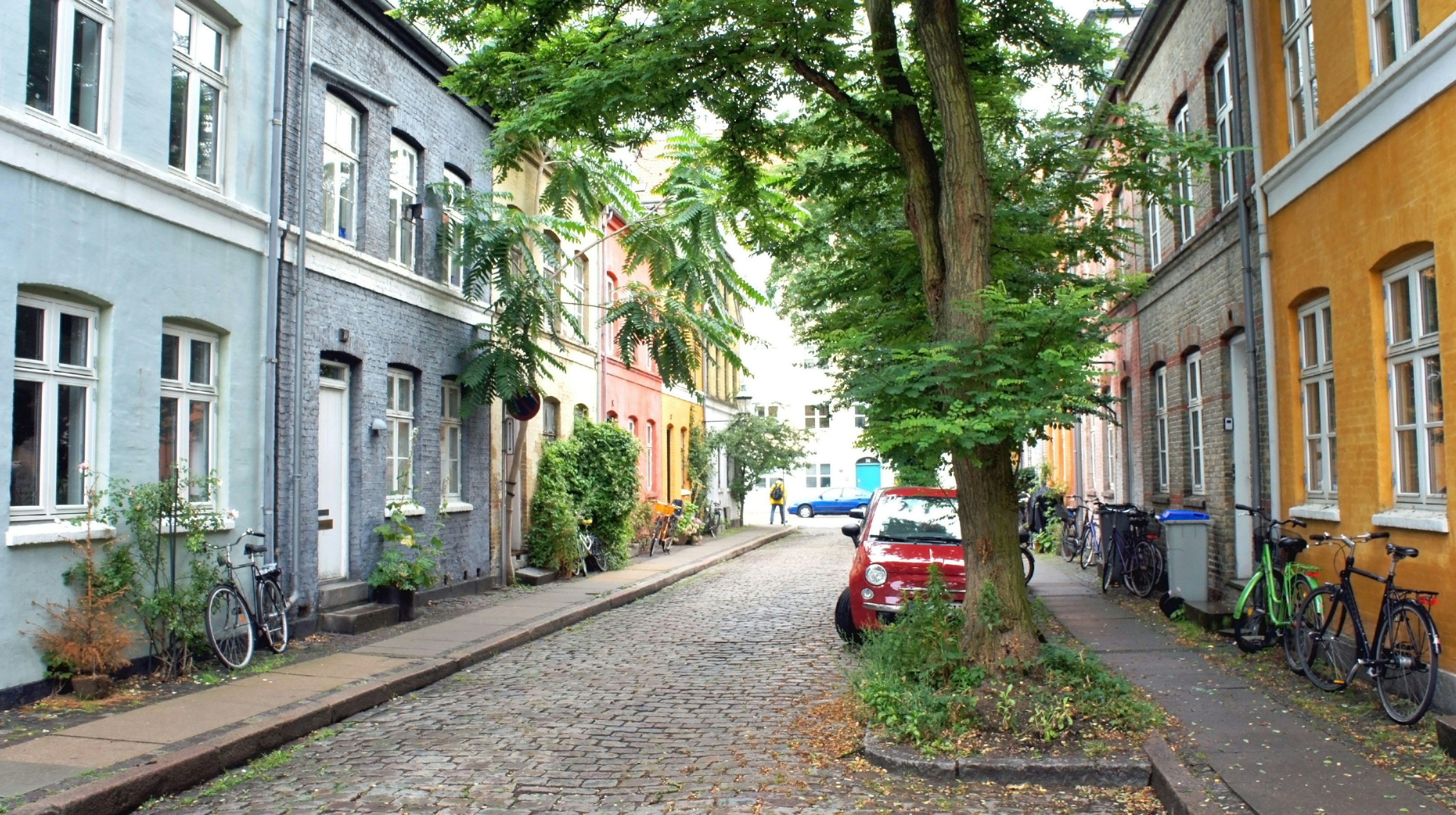 Cobblestone street in Denmark with bikes parked outside homes.