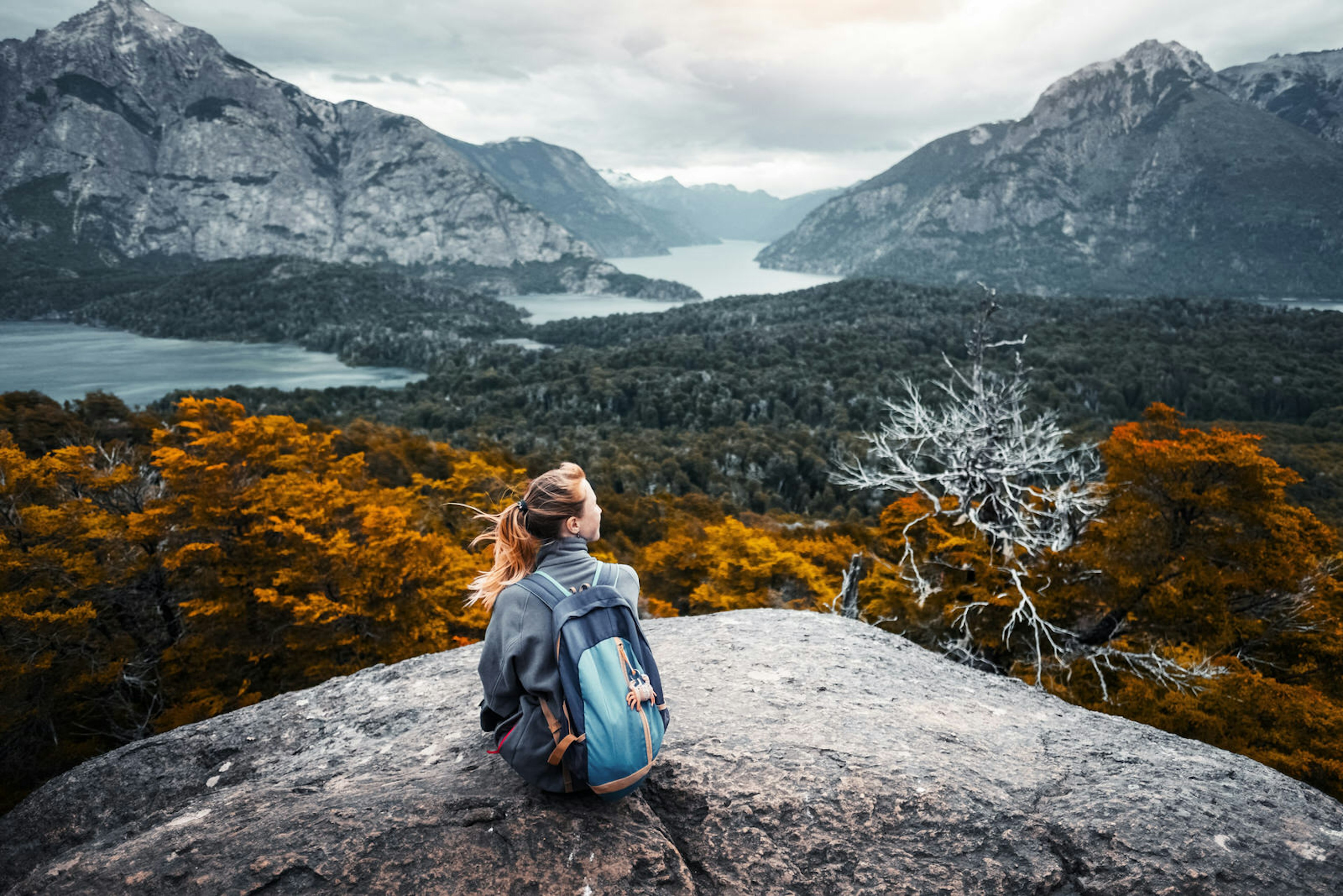 A traveller wearing a backpack enjoys an autumnal valley view in Patagonia, Argentina.