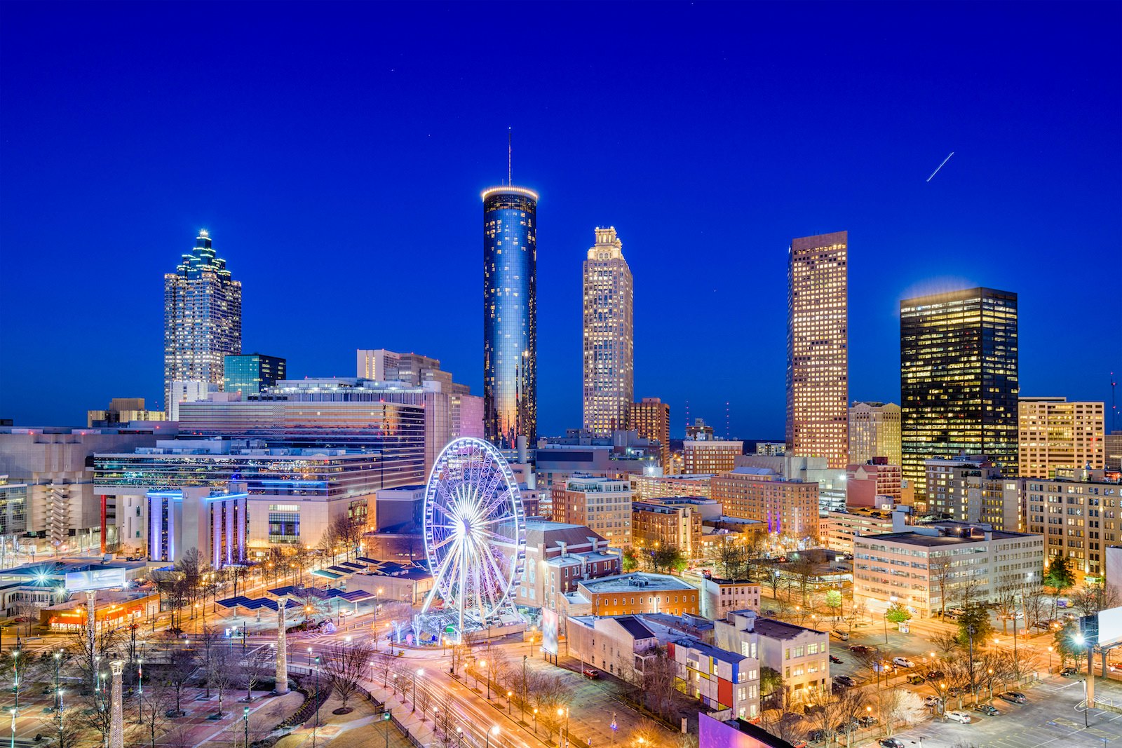 The Atlanta skyline at night- an indigo sky, lit ferris wheel and twinkling building lights