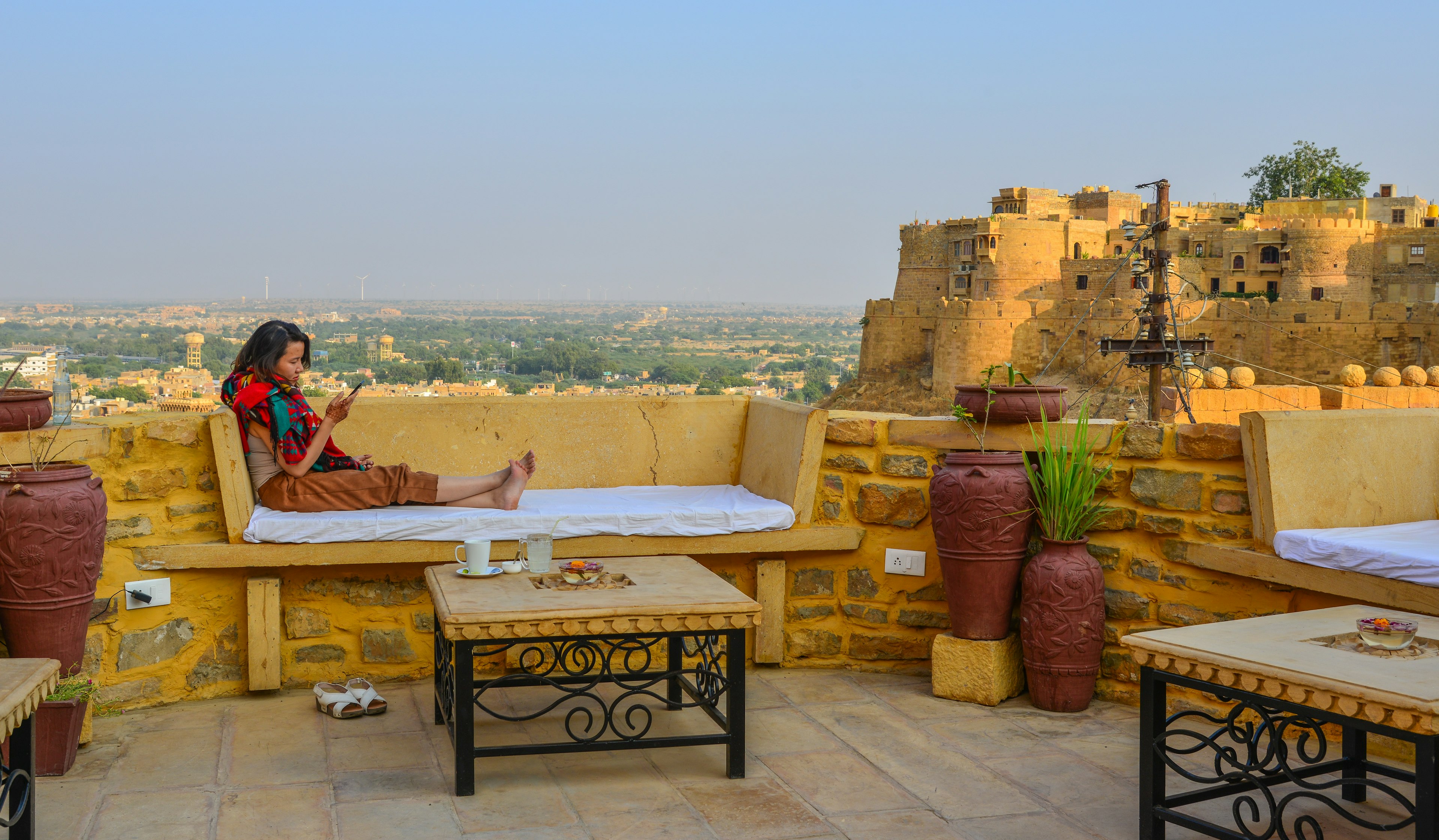 Woman enjoying coffee at a rooftop shop in Jaisalmer Fort.