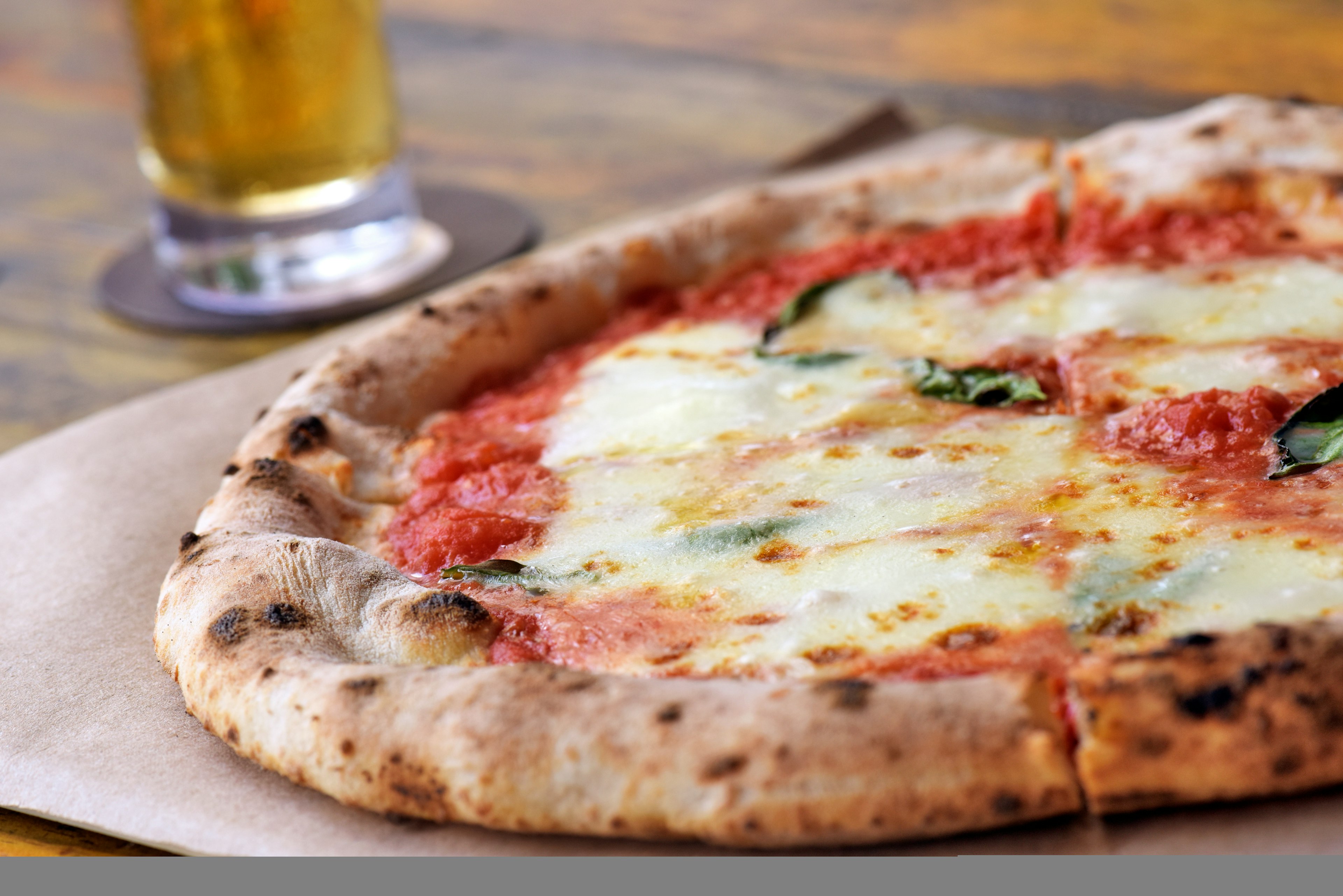 Margarita pizza on parchment paper, served with a beer in the city of Sao Paulo.