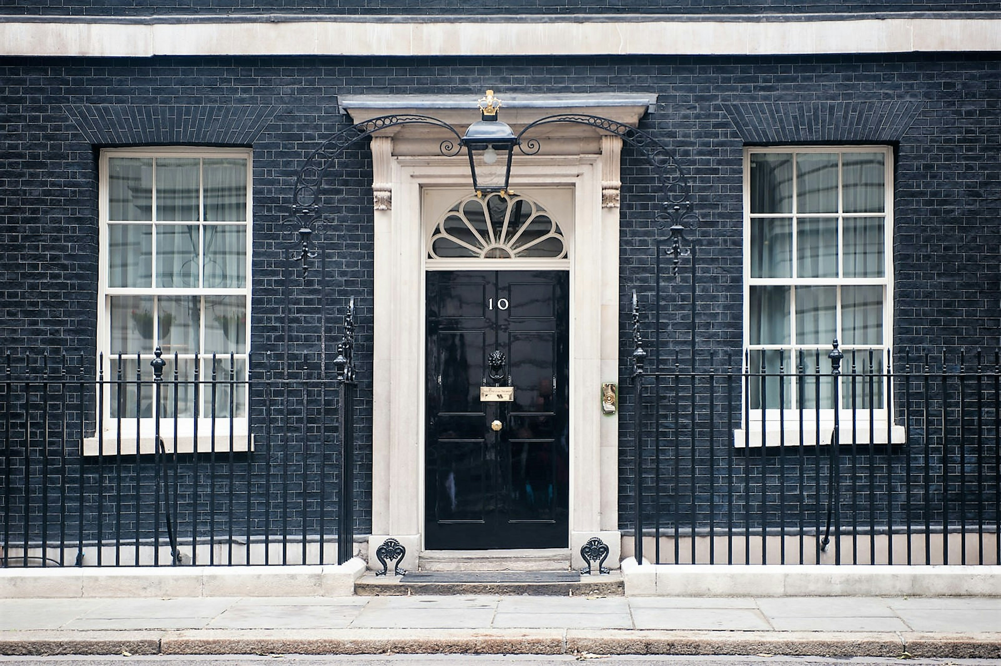 A black door with a number 10 on it set in a brick wall