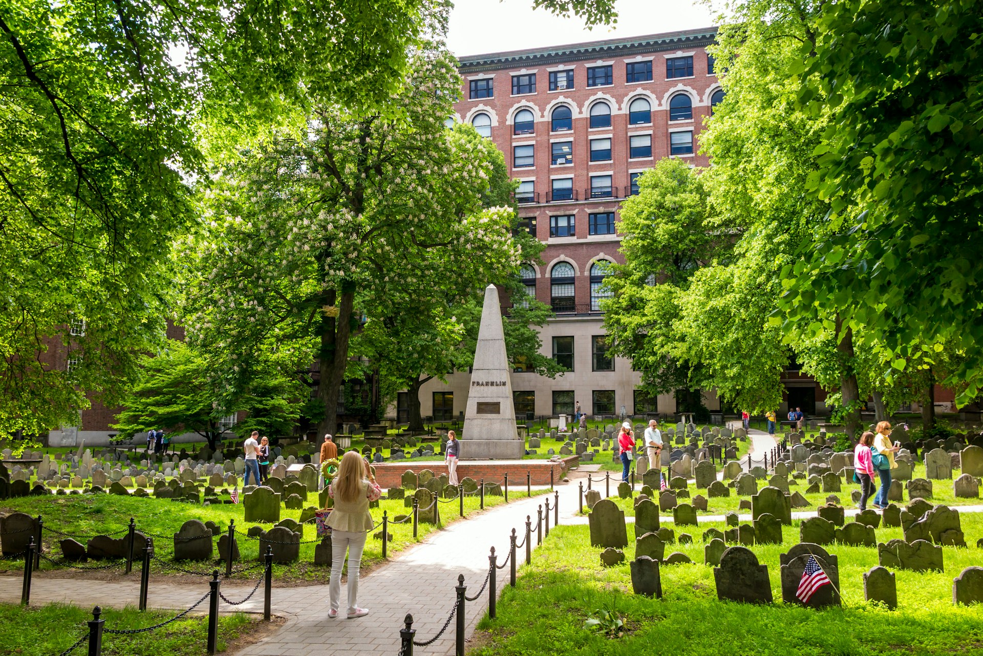 People walk about an ancient graveyard looking at the headstones