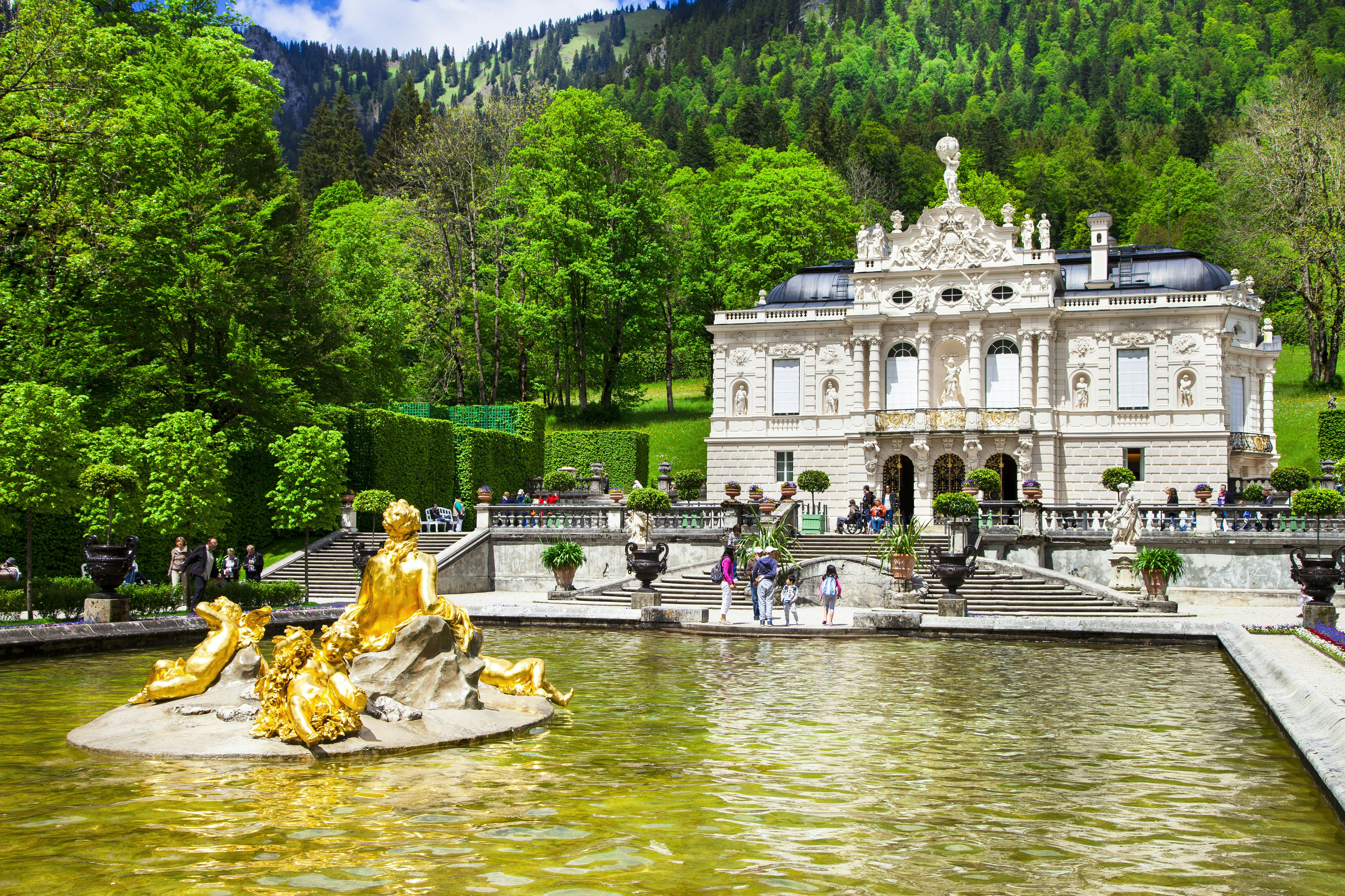 Visitors by the water at Linderhof Palace in summer with the Alps in the background, Bavaria