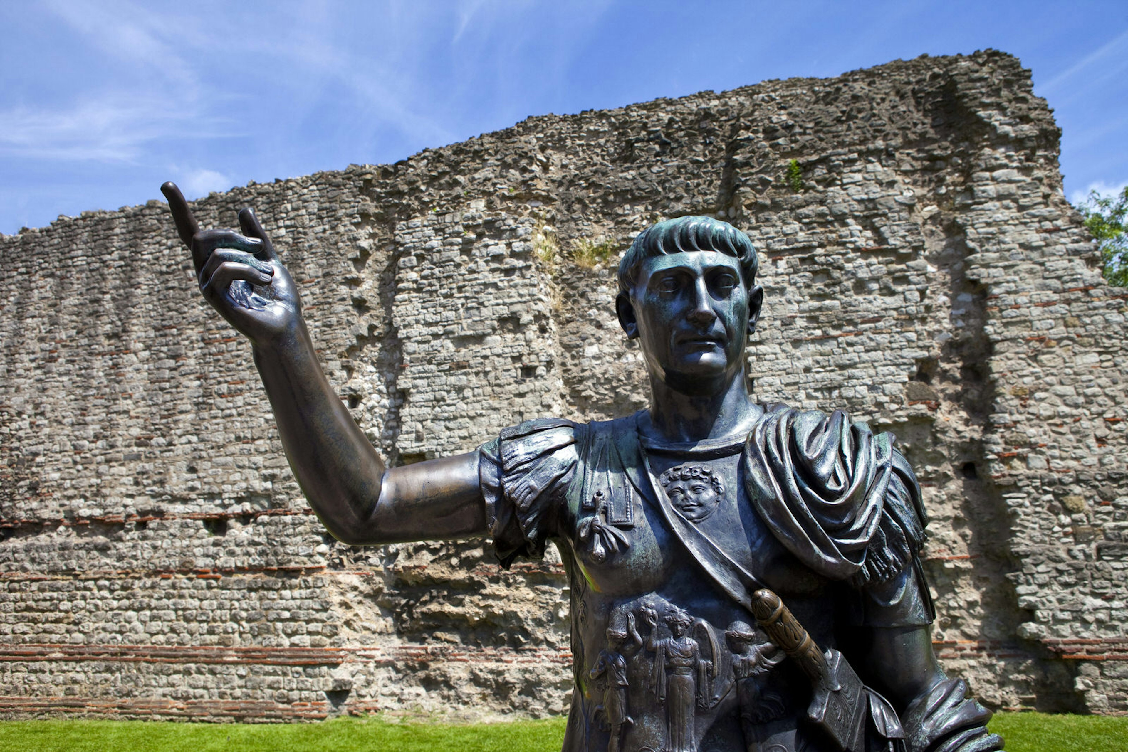 The Roman wall in London with a statue of the Emperor Trajan in front of it.