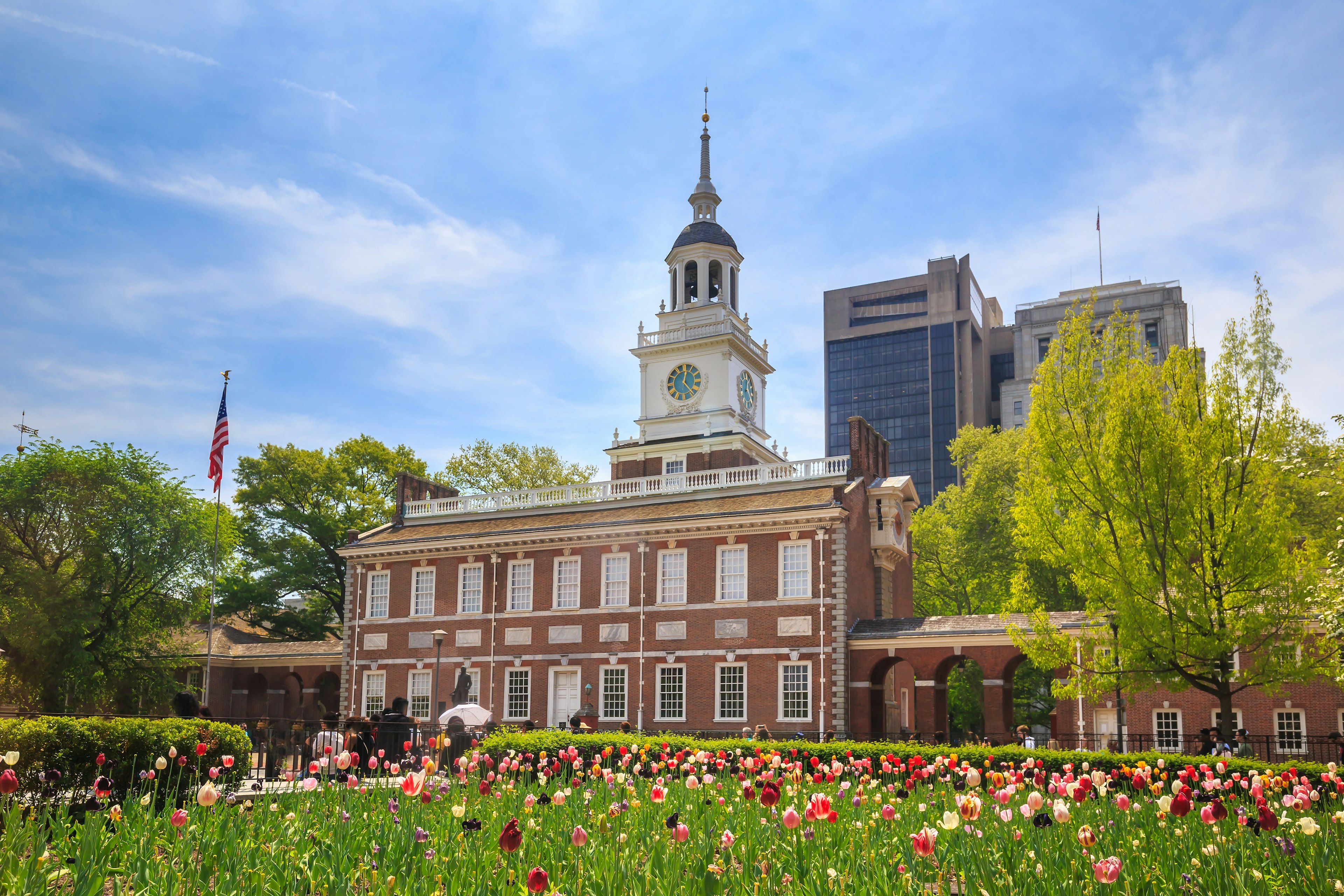 A red-brick building with a white bell tower near a garden of tulips