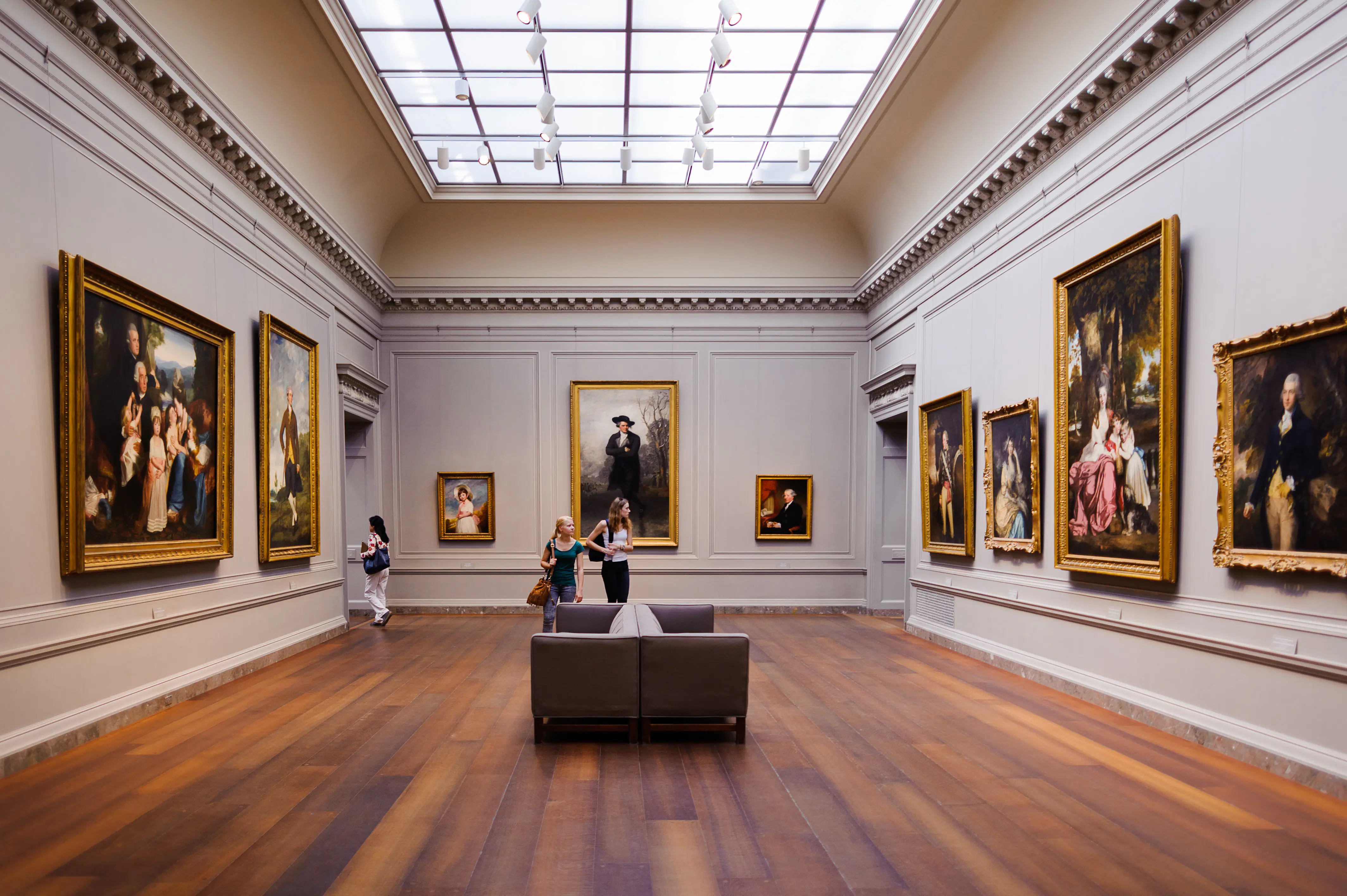 Interior of the National Gallery of Art, a national art museum in Washington, D.C. The walls are covered with giant paintings as visitors walk around the room