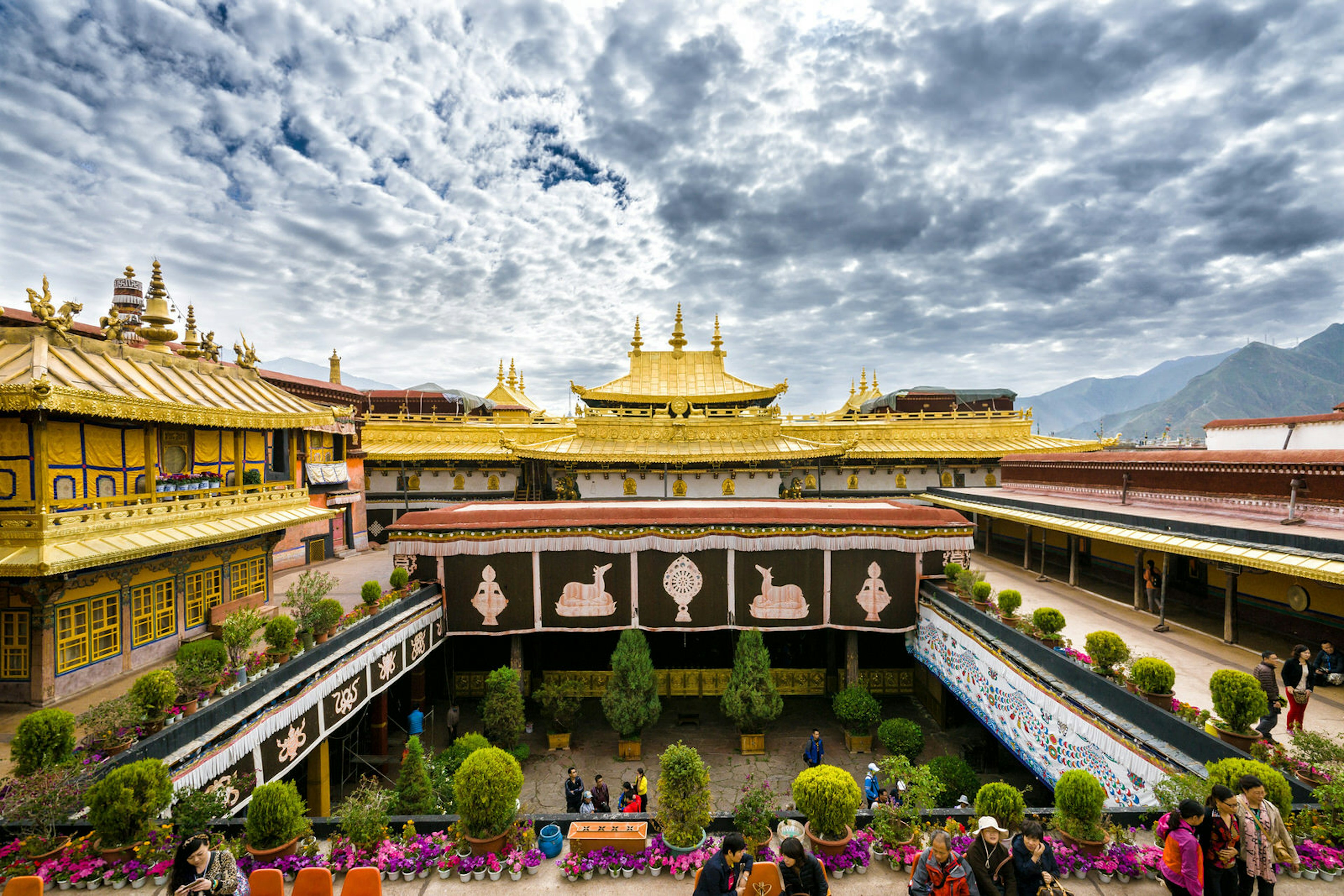 Clouds ripple across the sky above the opulent gold roof of Jokhang Temple, with the courtyard below