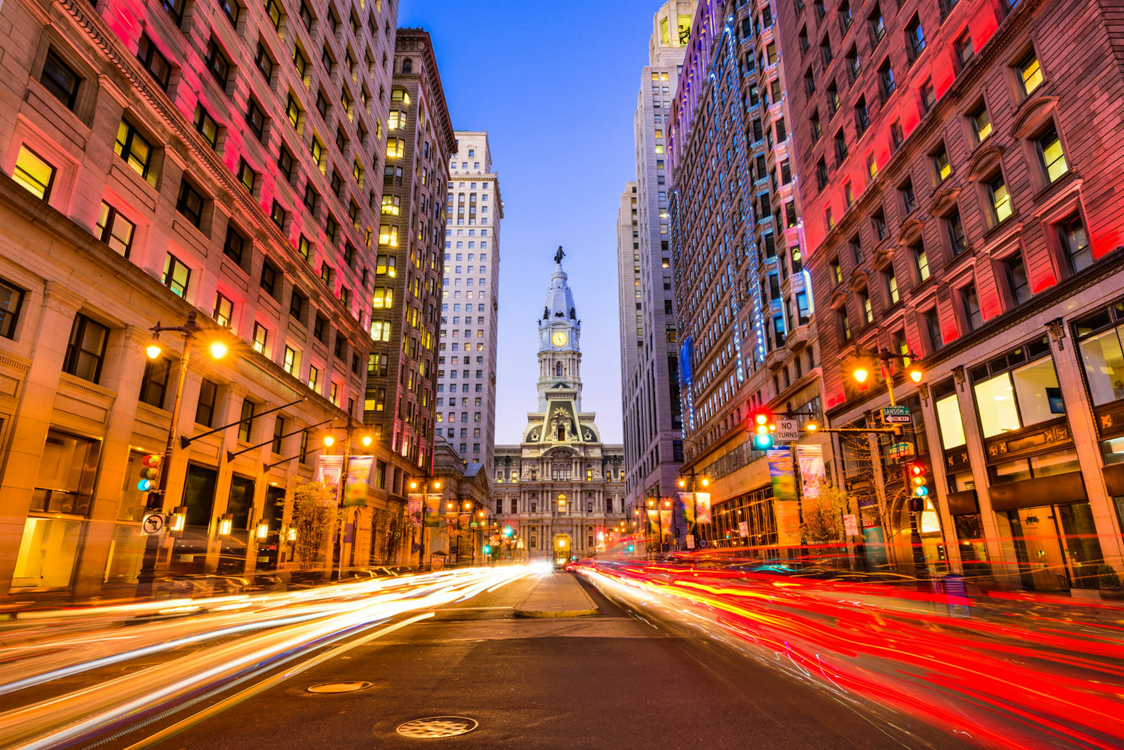 Long-exposure light trails along a Philadelphia thoroughfare at twilight.