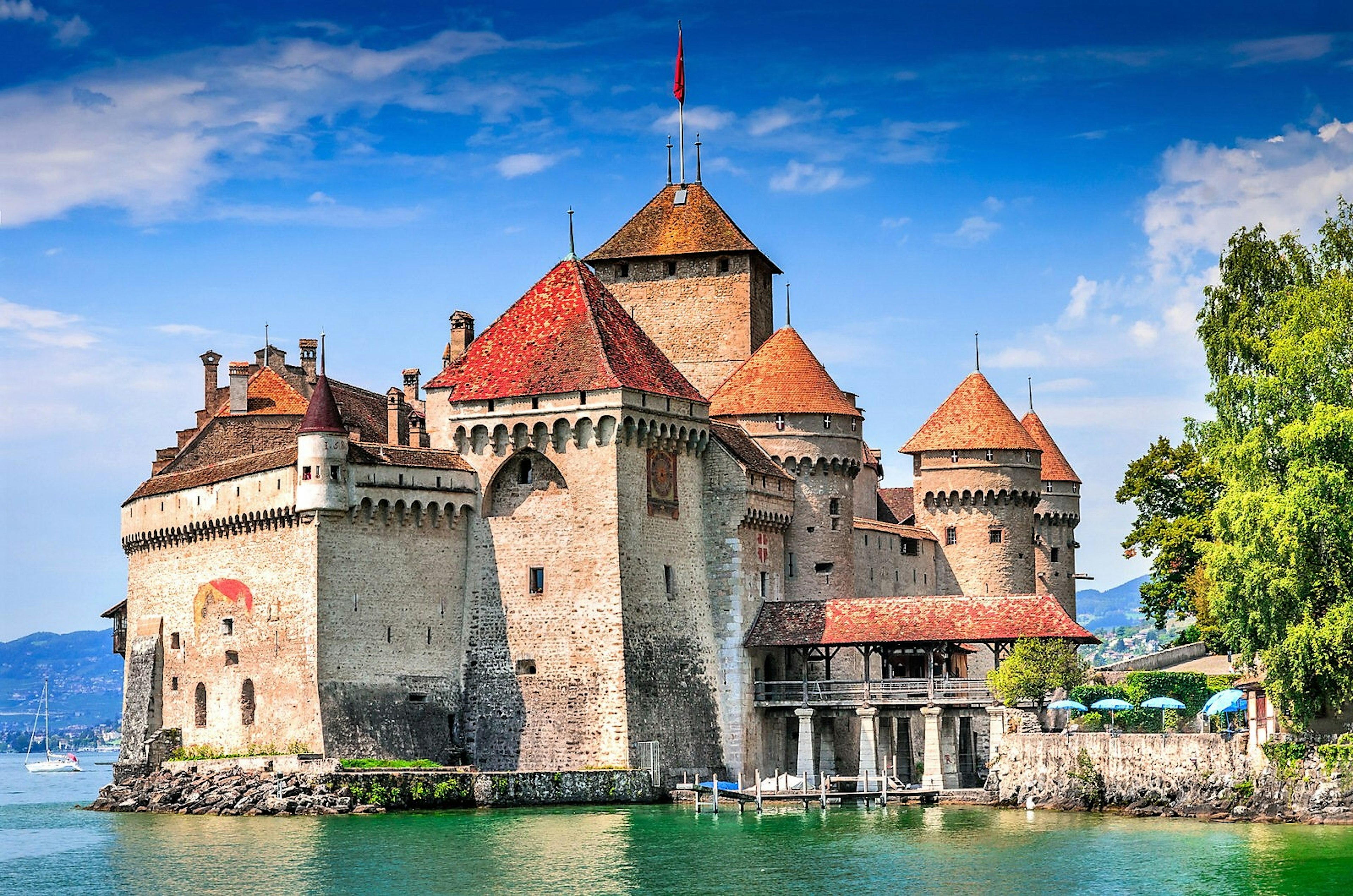 The towers of Chillon Castle reflect in the waters of Lake Geneva