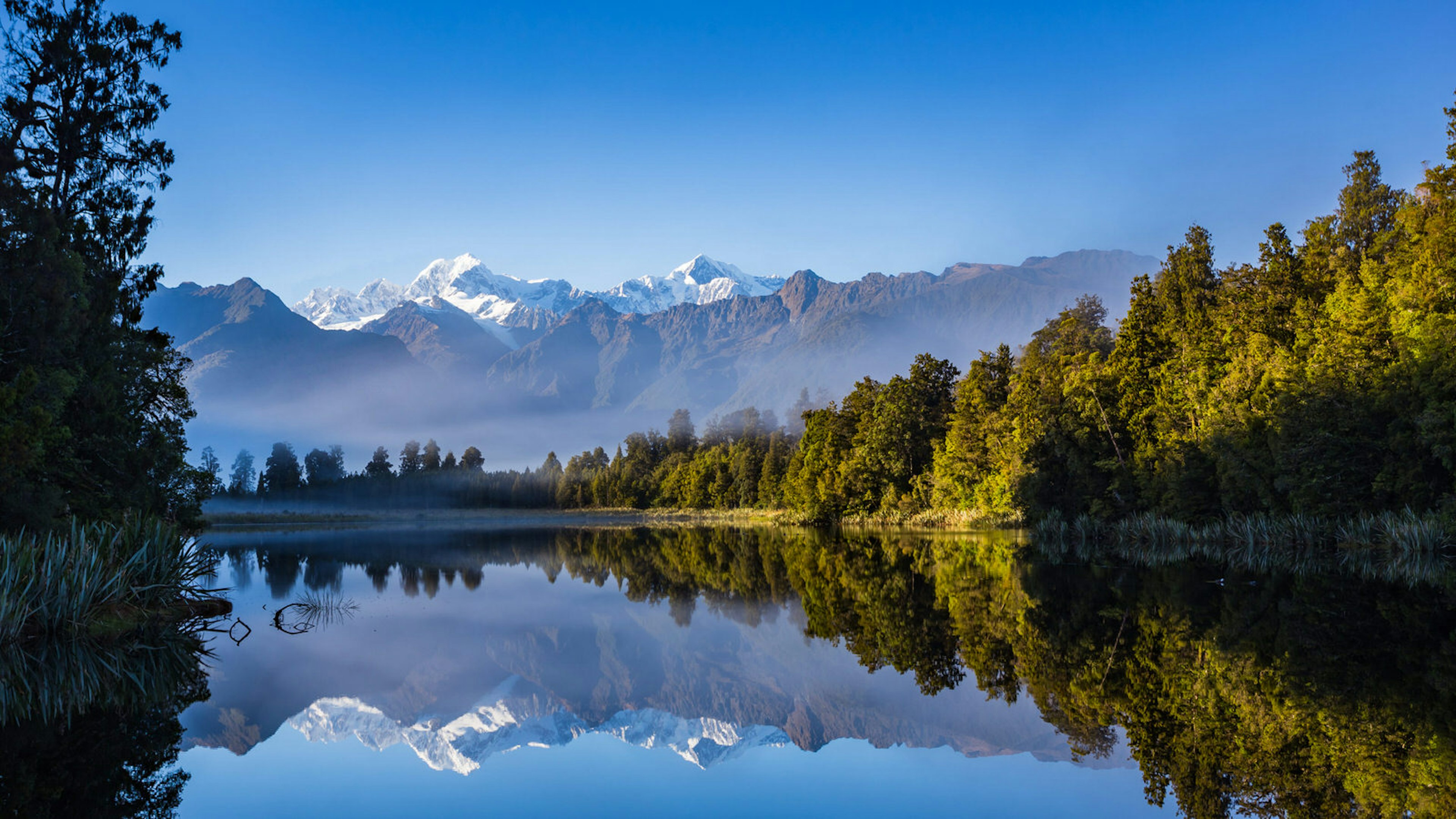 Reflection of snow-capped peaks in the still waters of Lake Matheson.