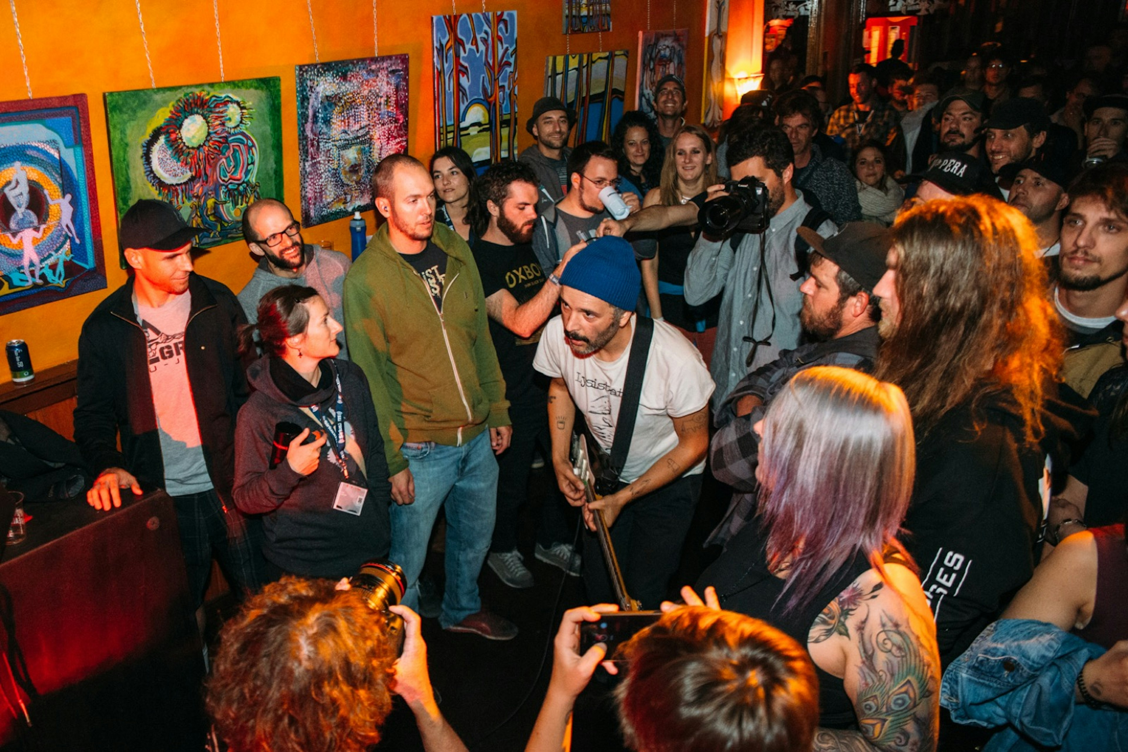 A guitarist plays as he walks through a crush of people in a very small venue © Festival de Musique Émergente