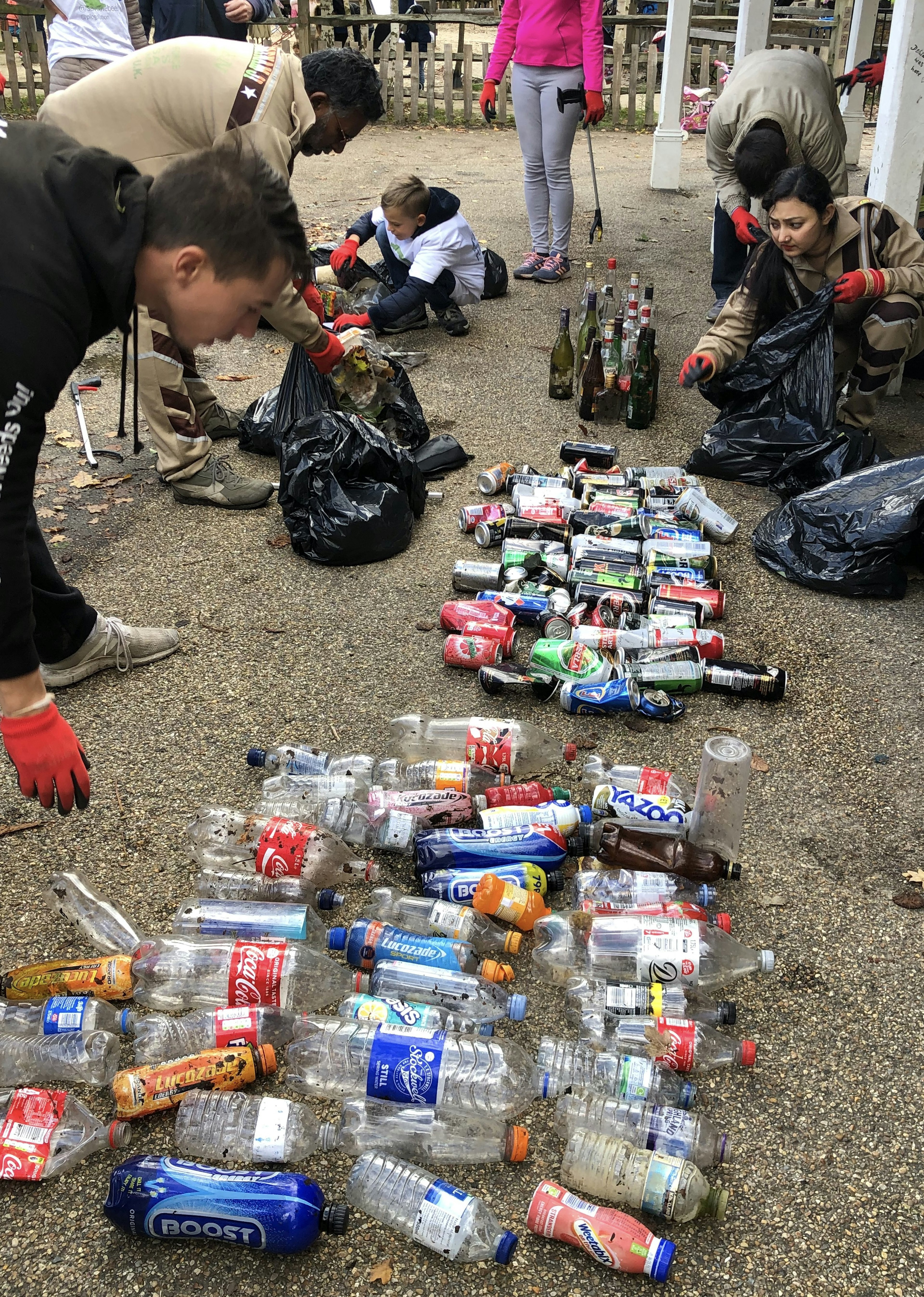 The group from Plogolution sort the results of their collection into recyclable and non-recyclable rubbish. With people of different genders and ages placing various waste items into black bags.