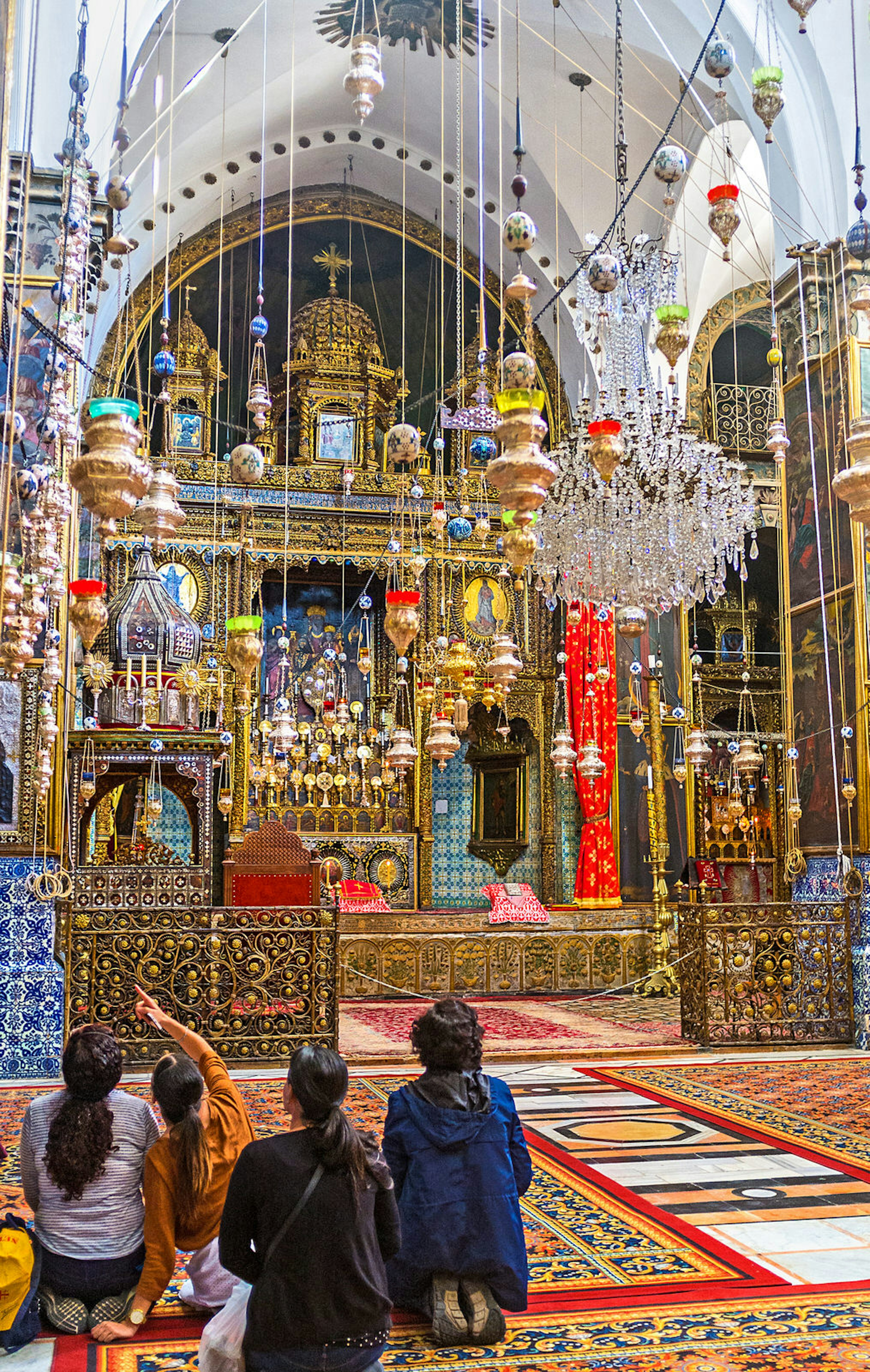 Pilgrims inside of the St James Cathedral with hundreds of oil lamps, wooden carved altar, covered with gold © efesenko / Getty Images