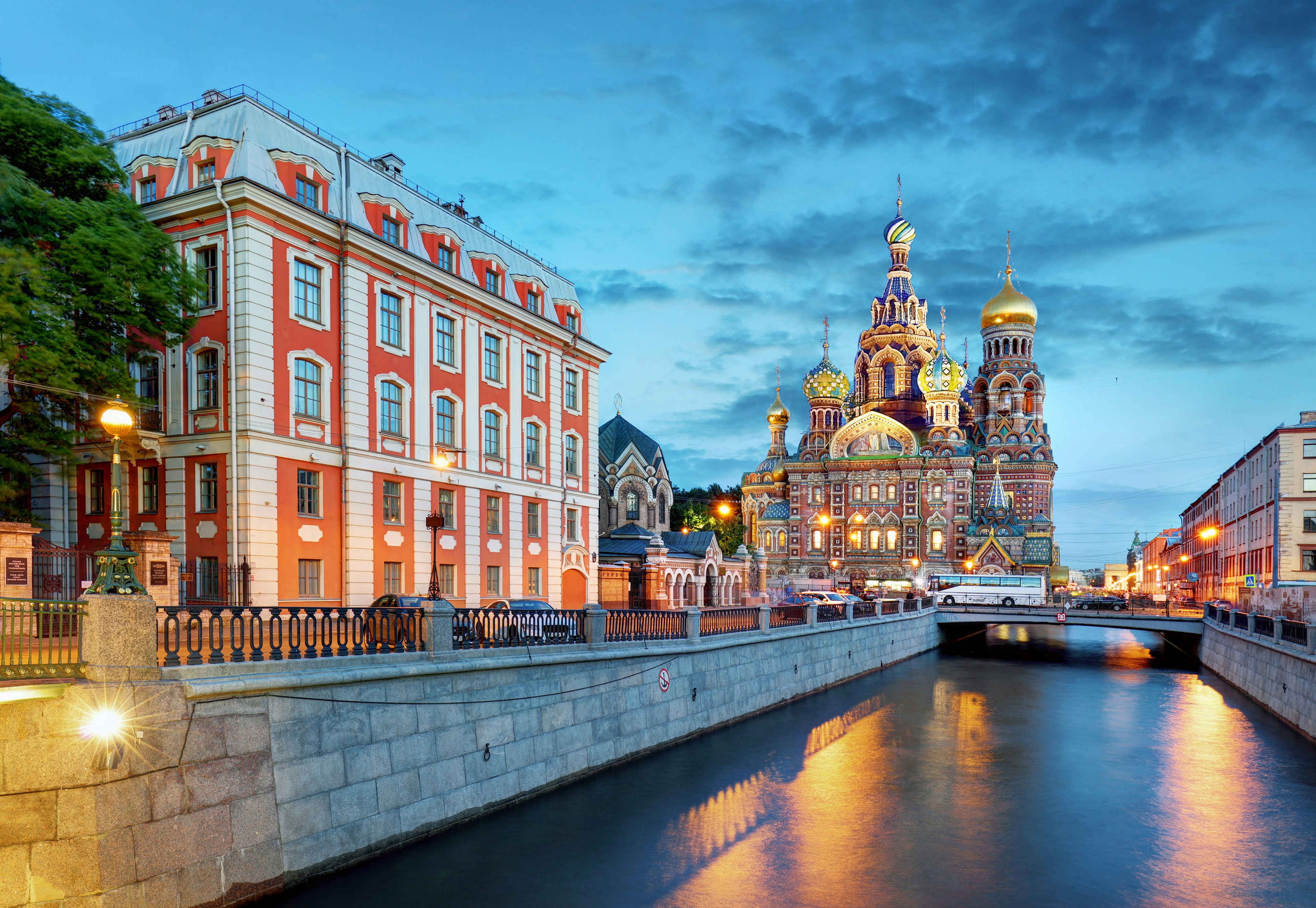 A scene looking down a canal towards the Church of the Saviour on Spilled Blood in St Petersburg at dusk.