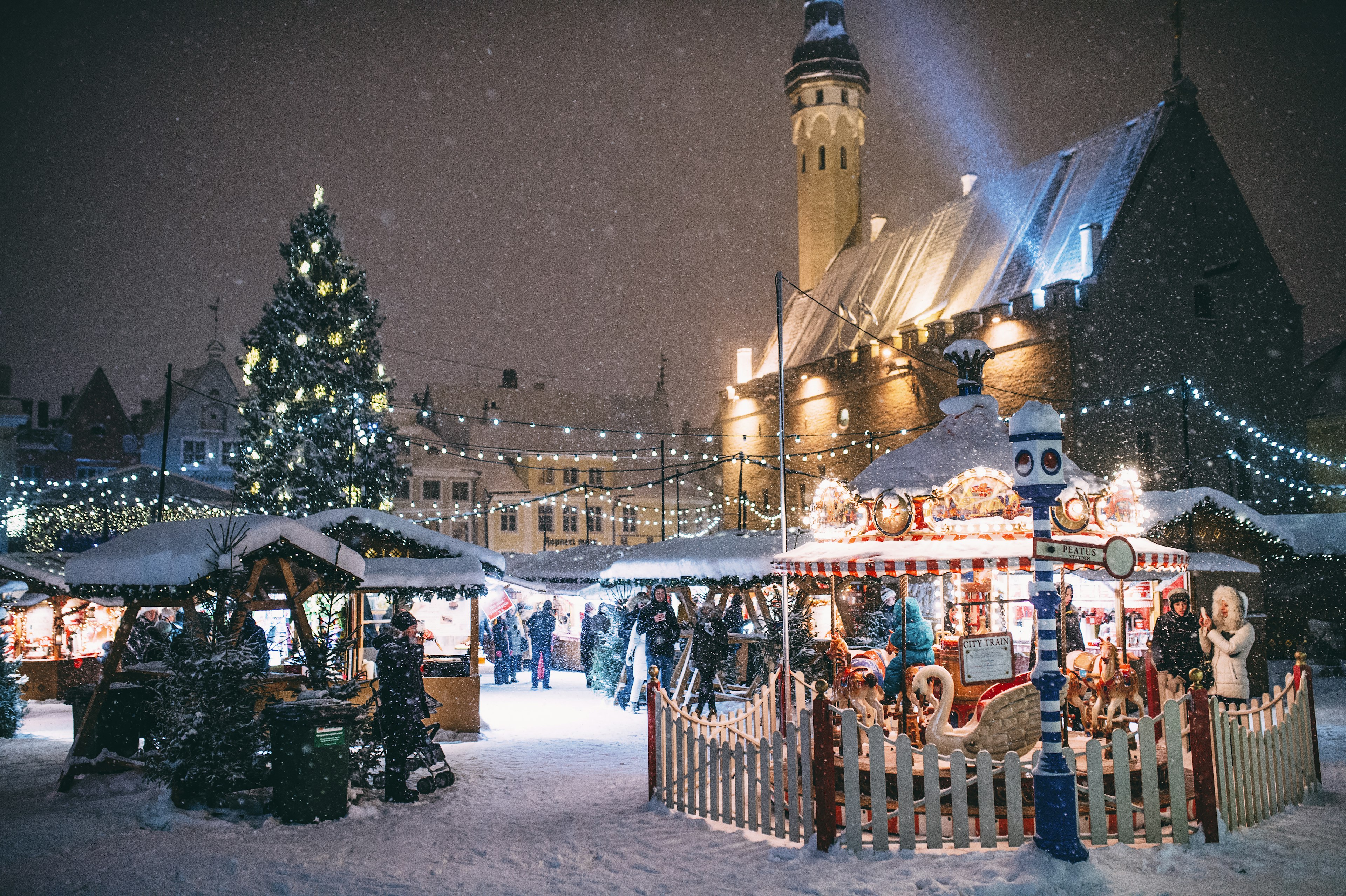 A Christmas tree covered in lights at night in the town square of Tallinn