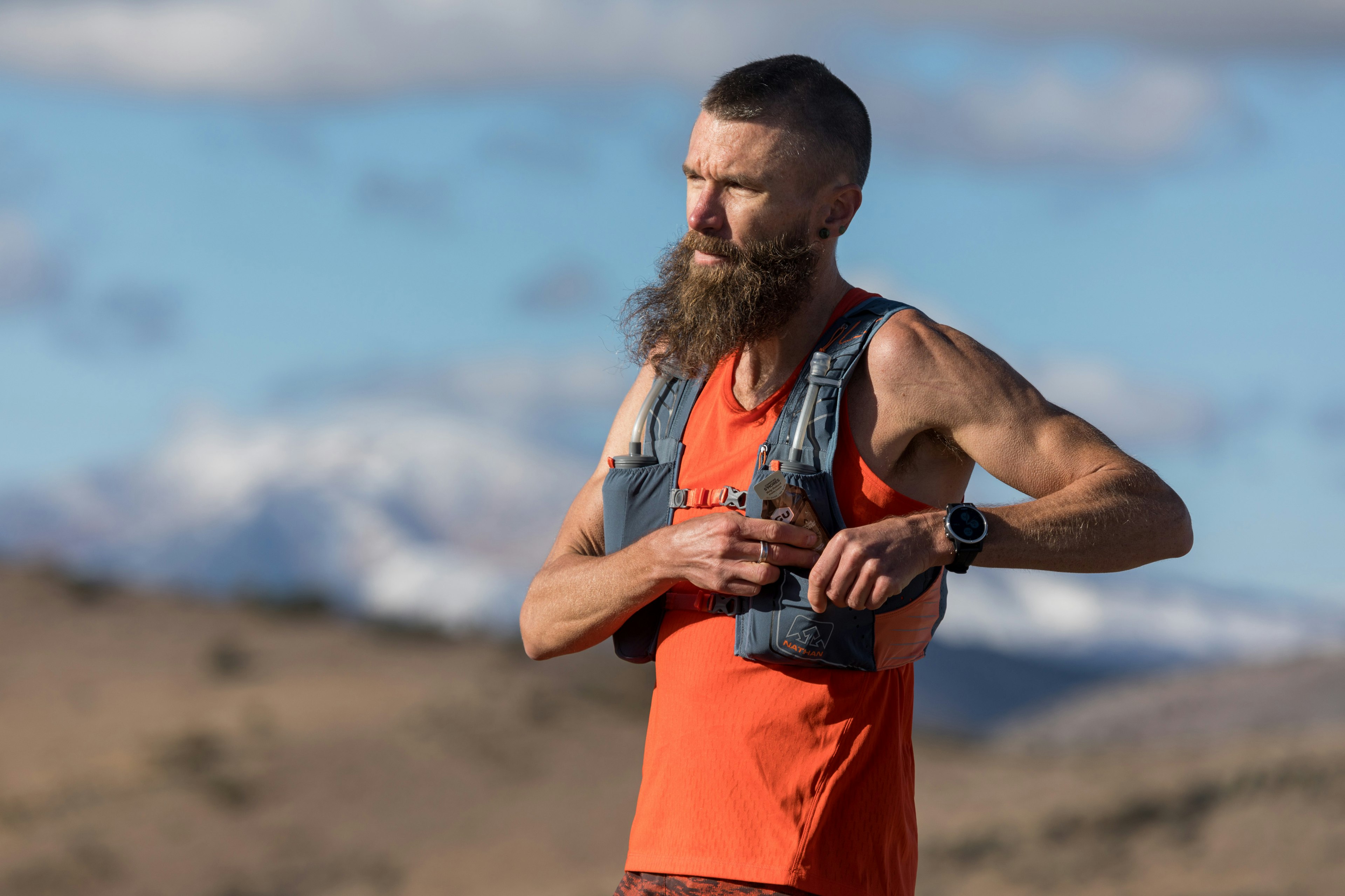 A man extracts a Gu nutrition pack from a running hydration vest