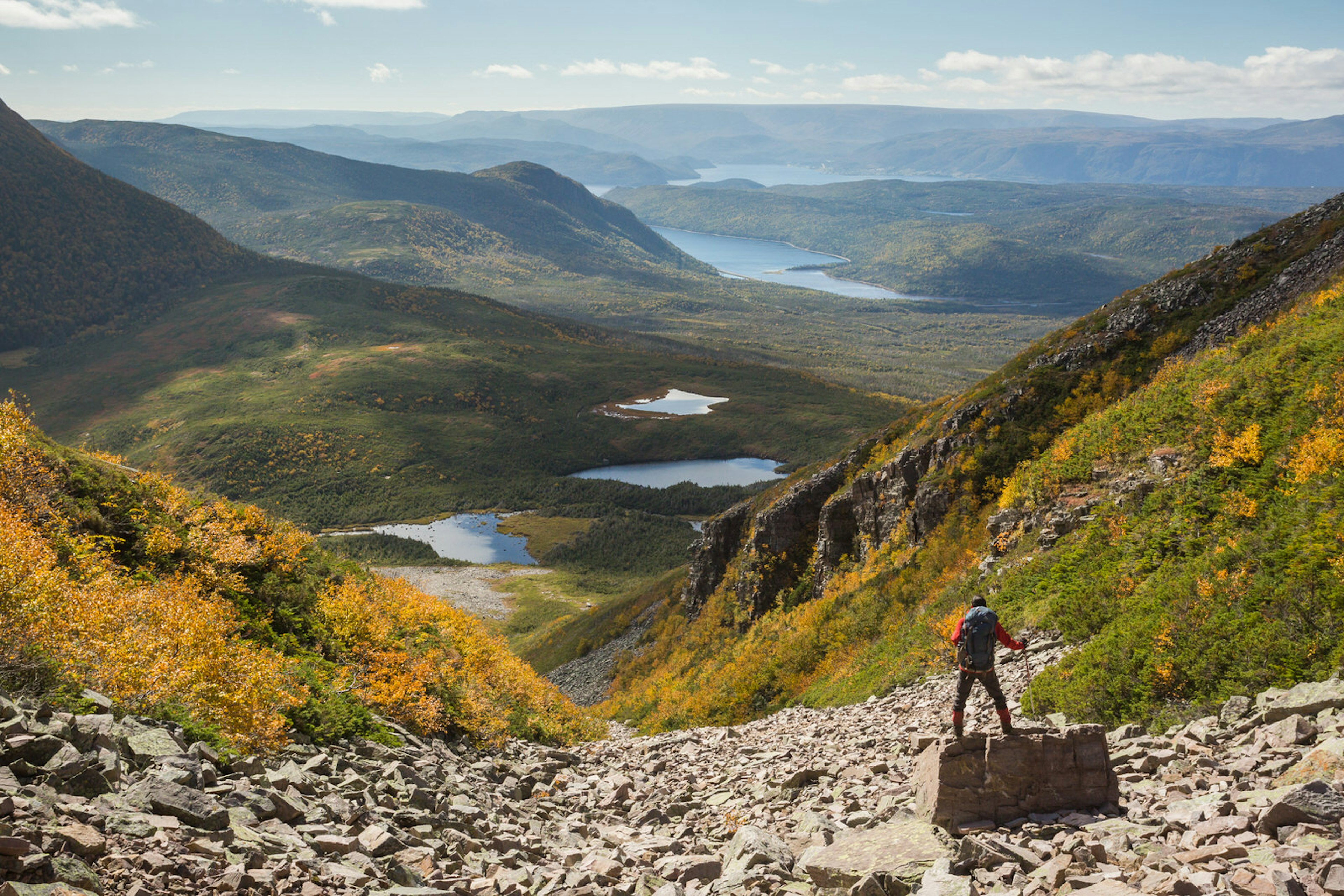 A hiker descending down Gros Morne Mountain with wonderful view of the countryside beyond