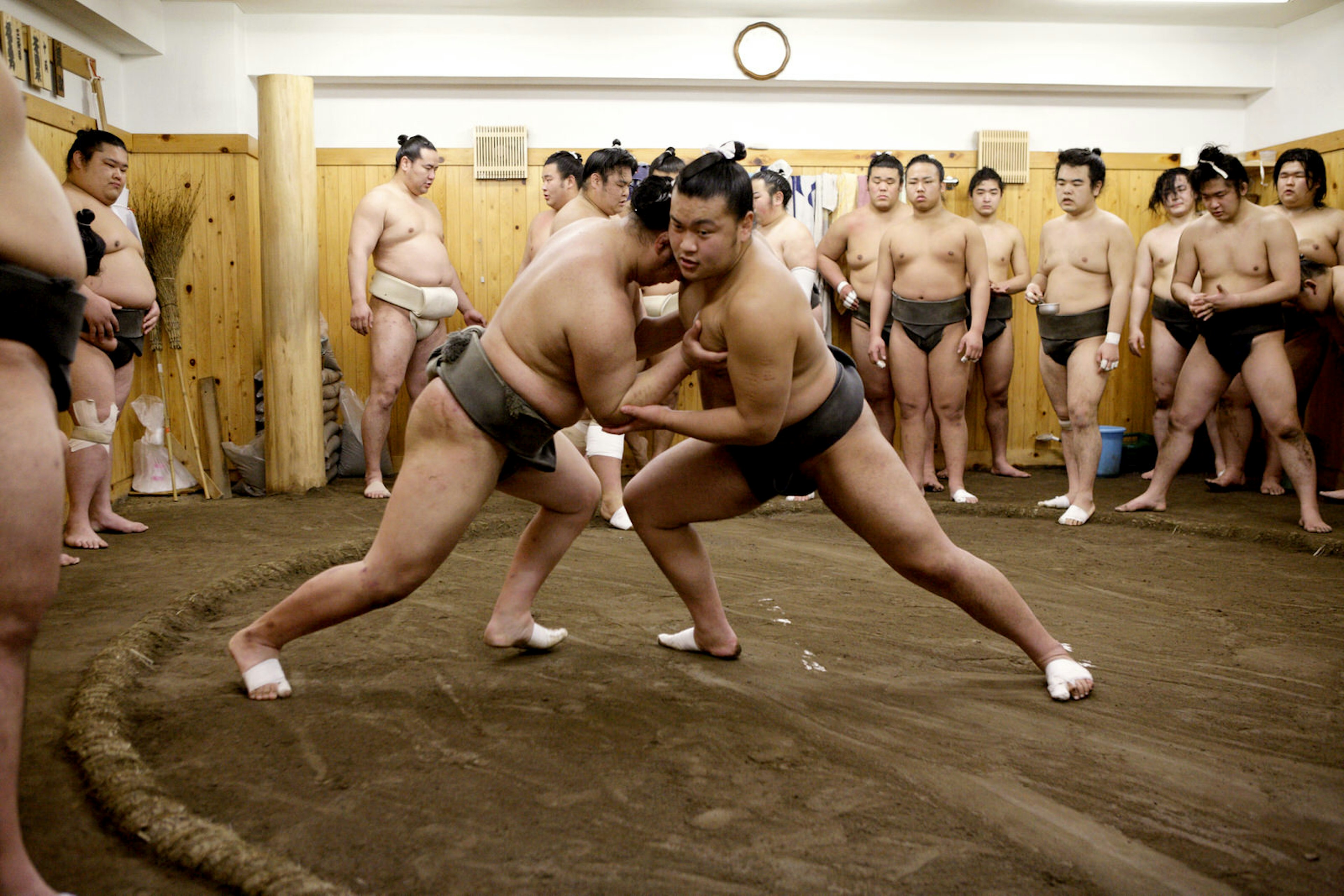 Young sumo wrestlers in Tokyo, Japan, practice while other wrestlers look on