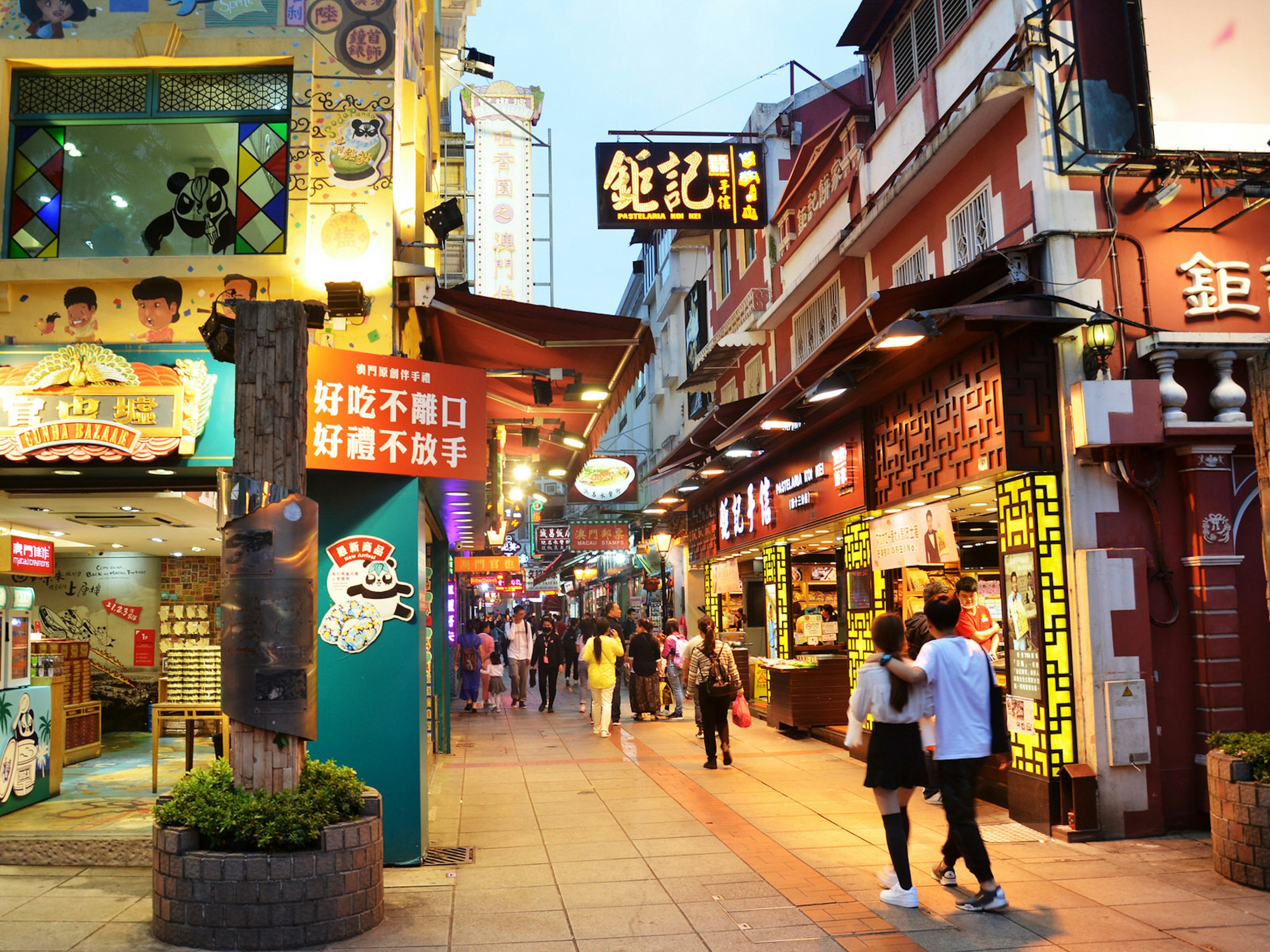 Early evening lights on along a busy food street. Rua do Cunha: Macau's unofficial food street