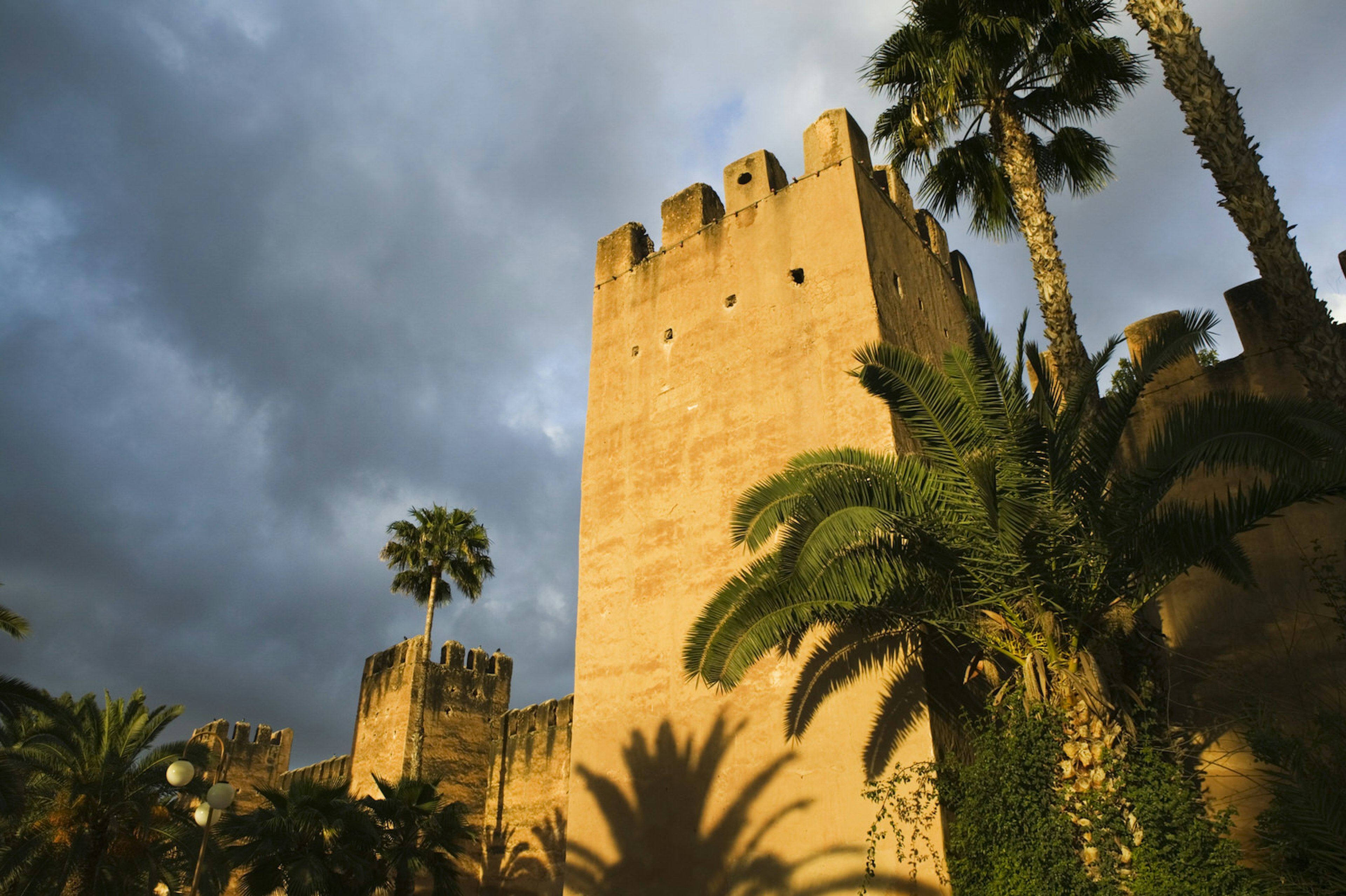 Exterior sand-coloured ramparts of the Hotel Palais Salam Palace with palm trees, Taroudant, Souss Valley, Morocco