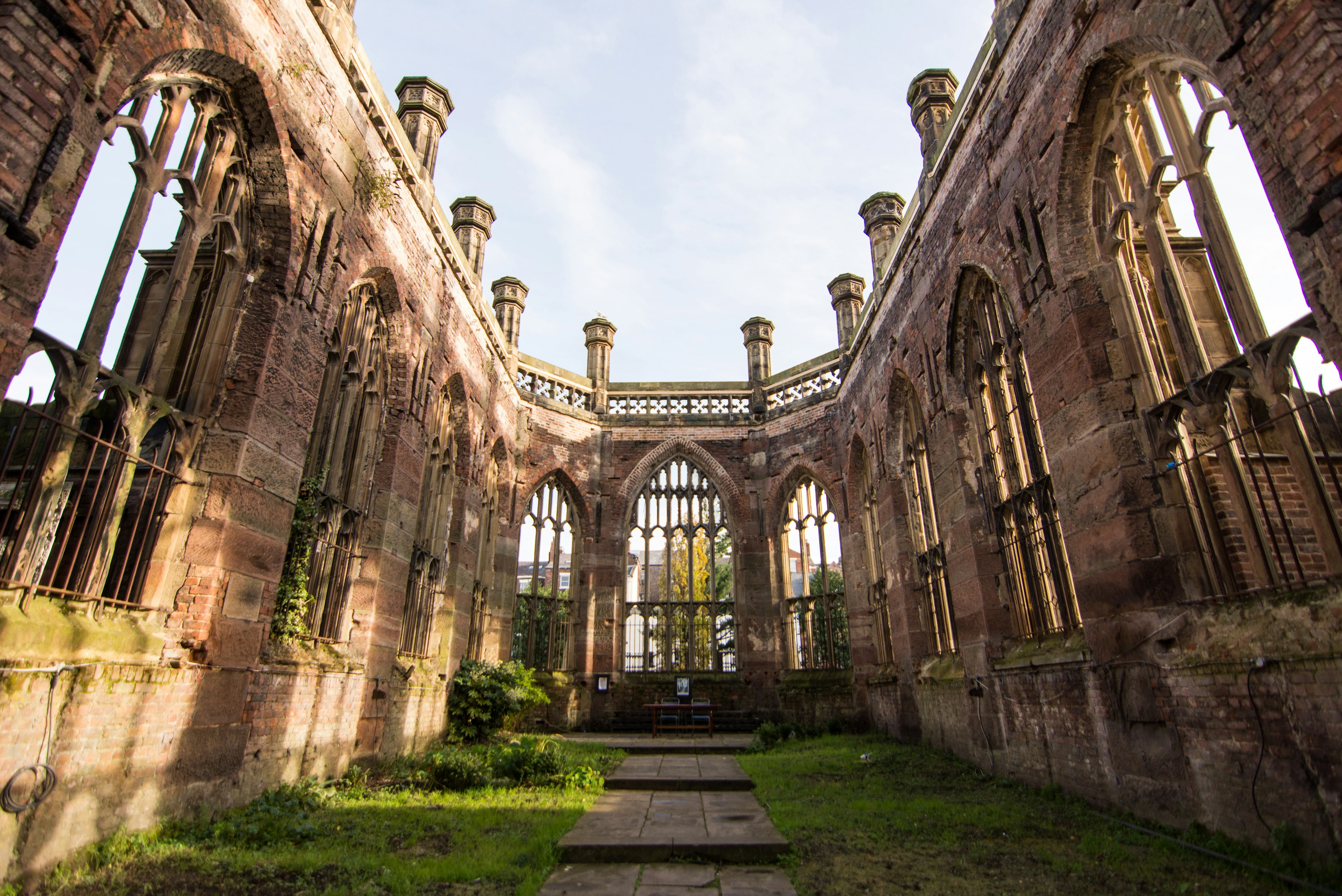 The interior of St Luke's Church in Liverpool; it has no roof or glass in the windows, and grass has grown on the ground inside it.