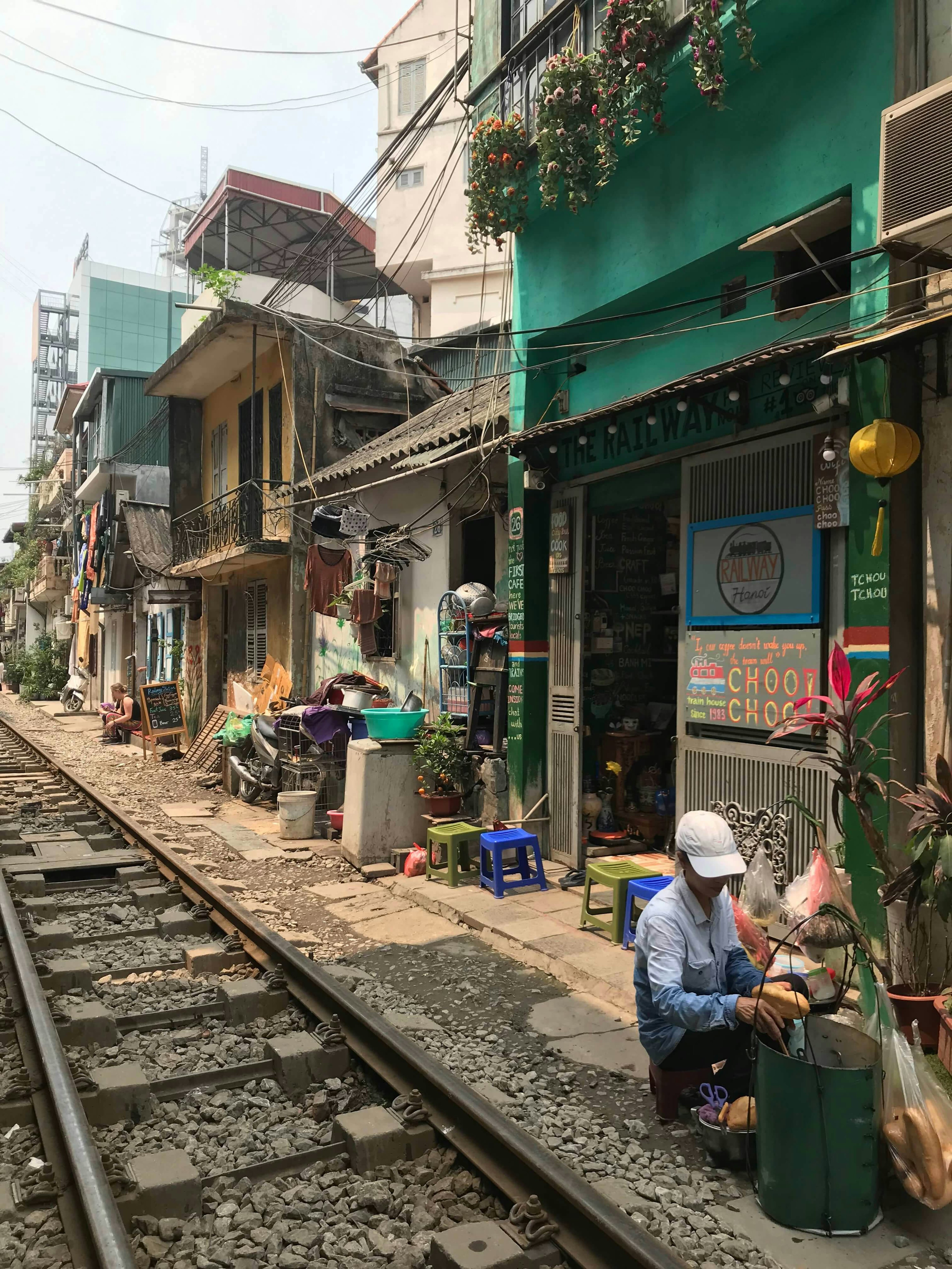 The outside of a cafe, right along the train tracks.