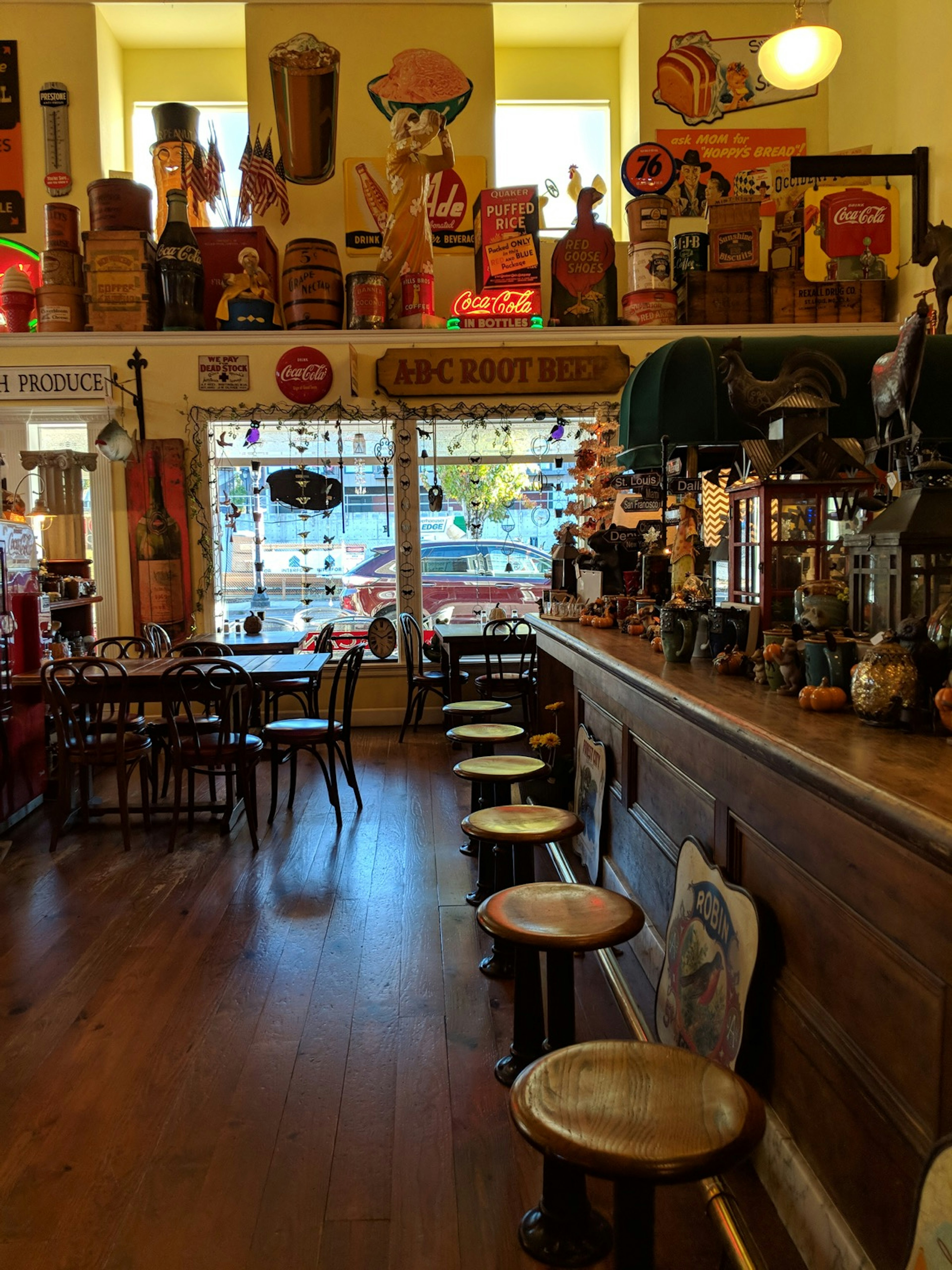 Old wooden stools and a polished wooden counter are surreounded by a cluttered collection of kitschy items