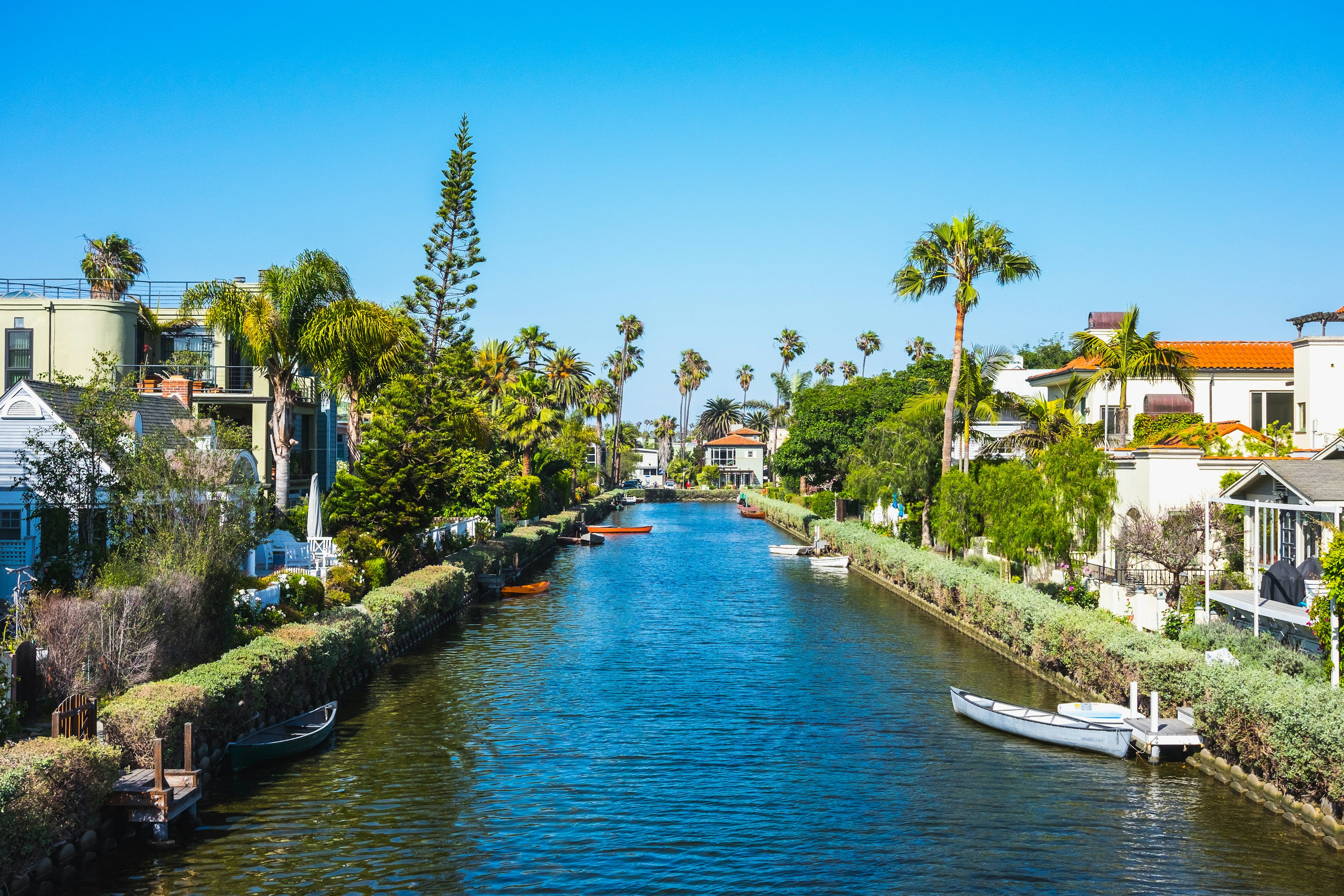 A canal is fringed with hedges and, behind them on either side are quaint cottages.