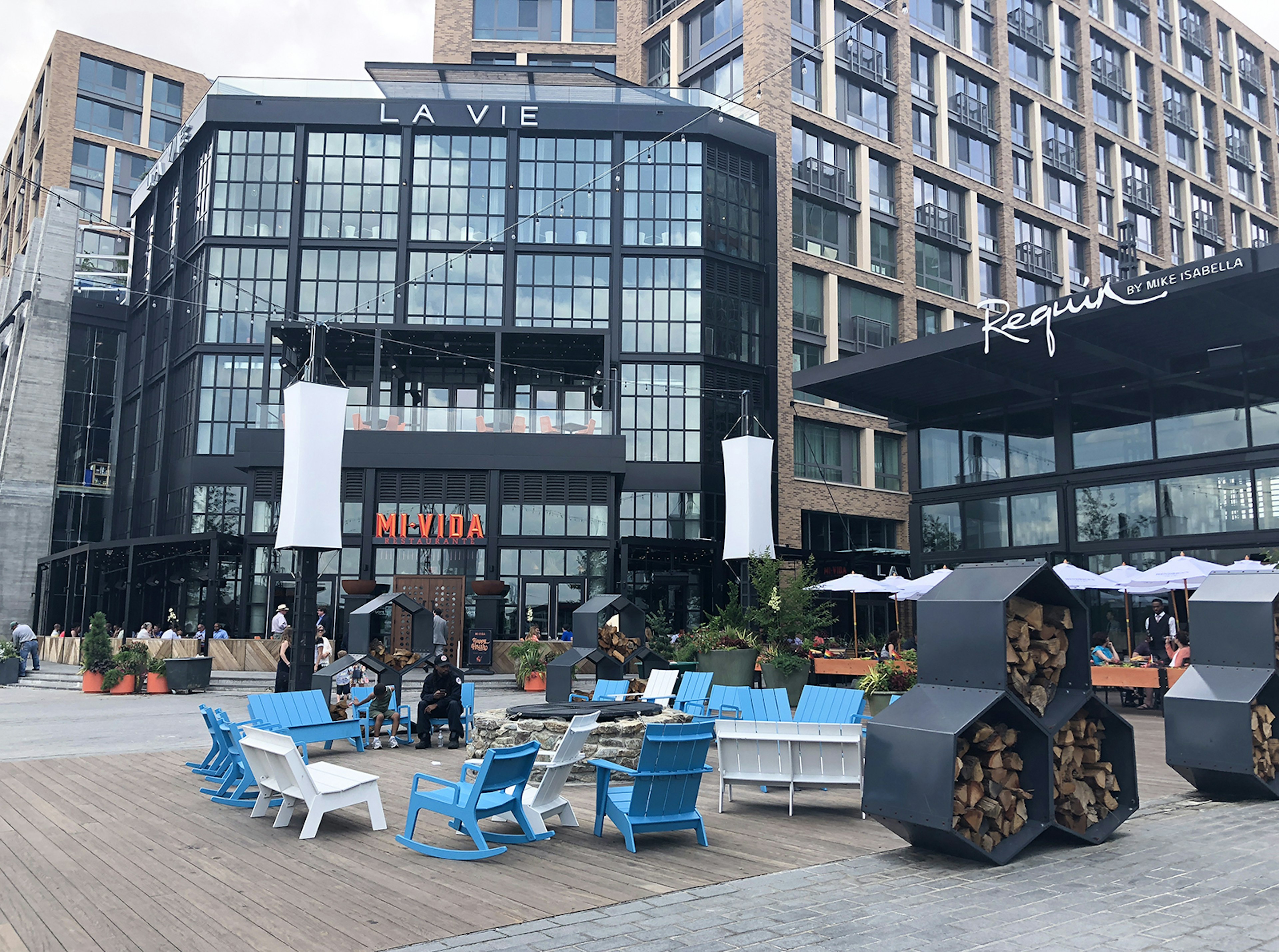 Blue and white adirondack chairs cluster around a firepit on the District Wharf © Trisha Ping / iBestTravel