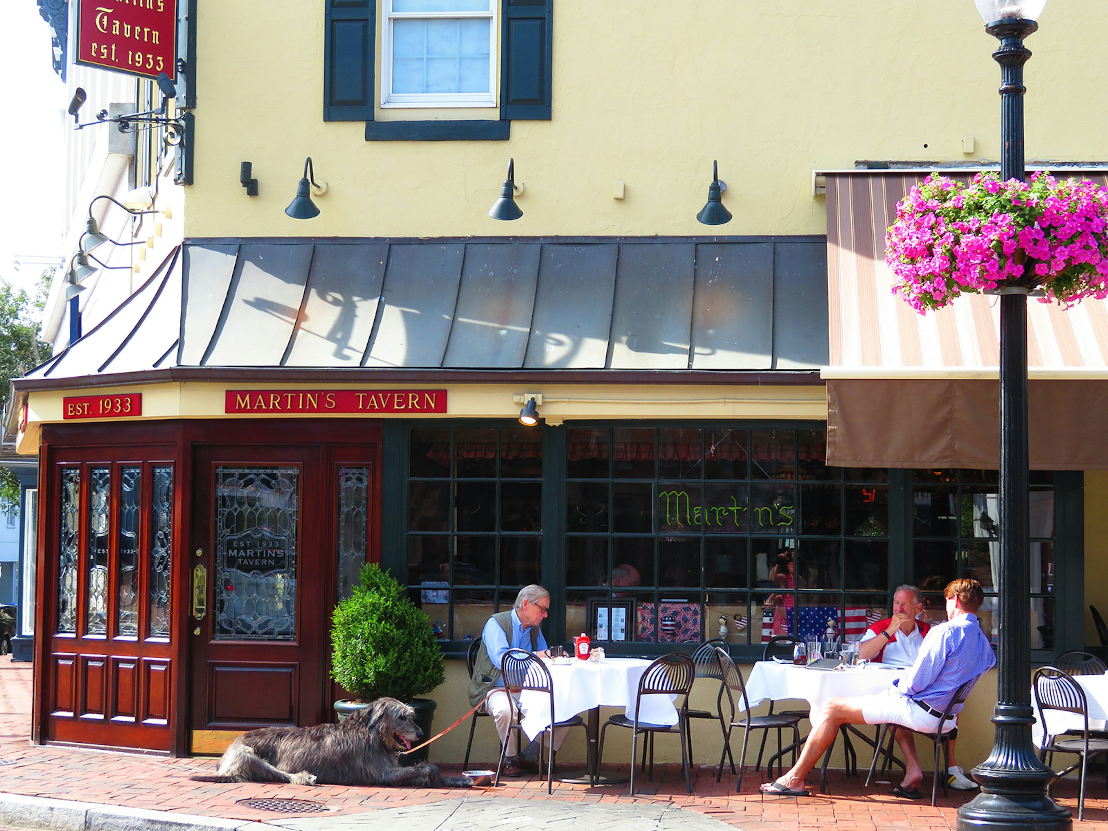 Three men and a large gray dog sit outside at cafe tables with white tablecloths on a sunny day in Washington DC © Barbara Noe Kennedy / Lonely Planet