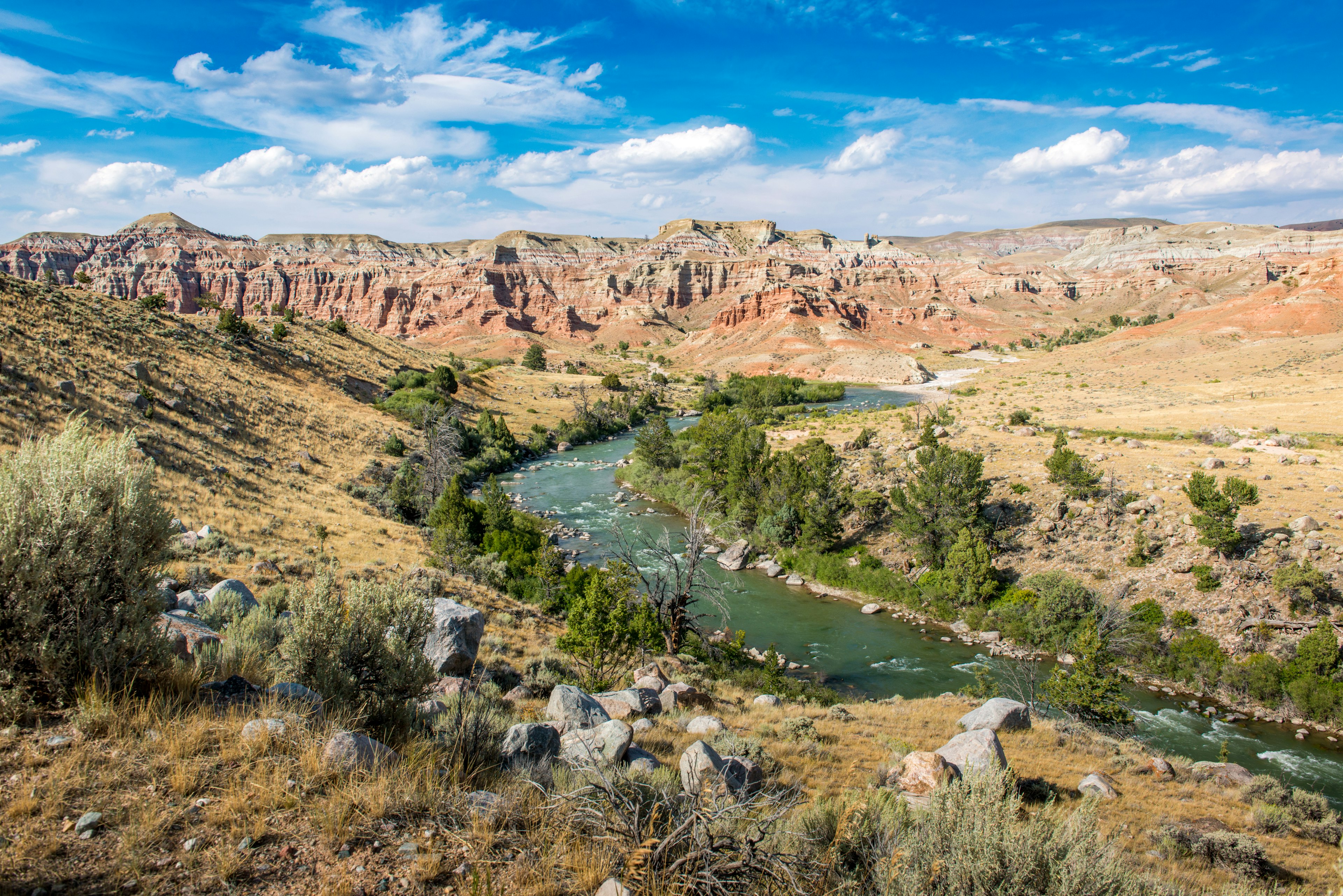 A river winds through an arid landscape of sagebrush and painted hills